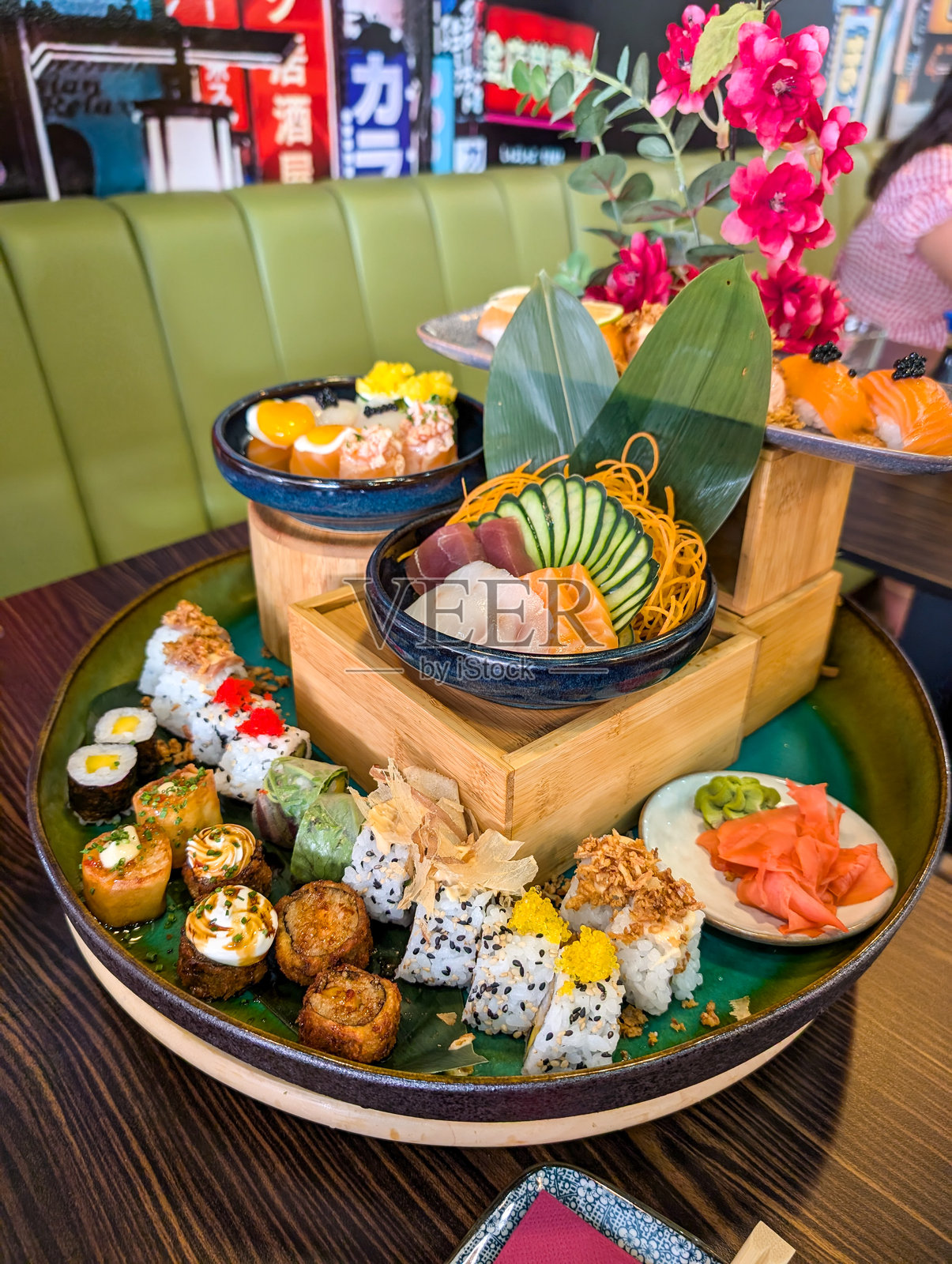 在日本餐厅里，一只大型寿司船上摆满了各种寿司、刺身、卷寿司和握寿司，配有腌姜和芥末，准备好让人享用。照片摄影图片