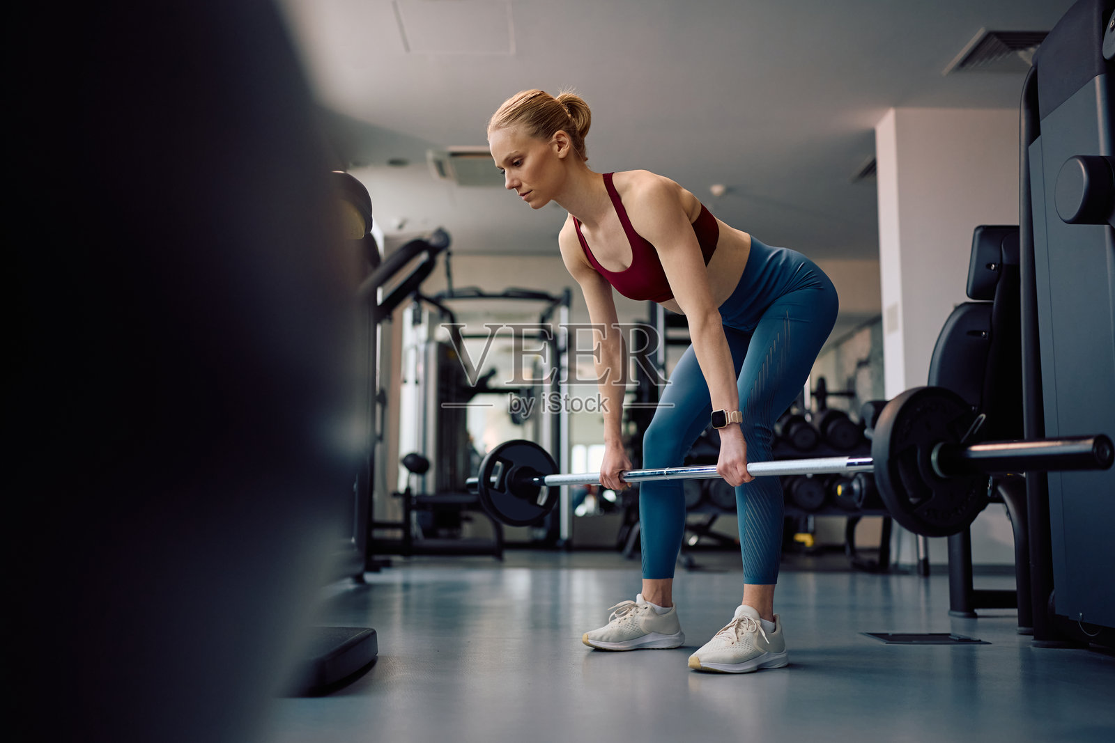 年轻的运动女性在健身俱乐部进行杠铃力量训练。照片摄影图片