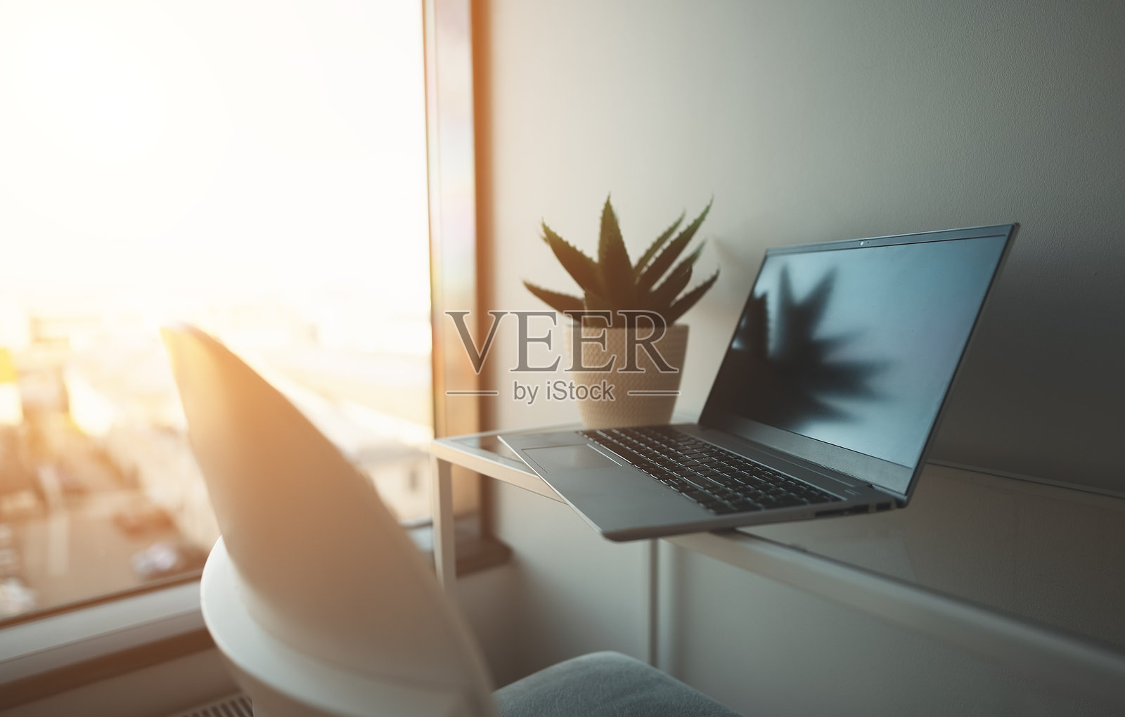 办公室工作区窗边的笔记本电脑。照片摄影图片