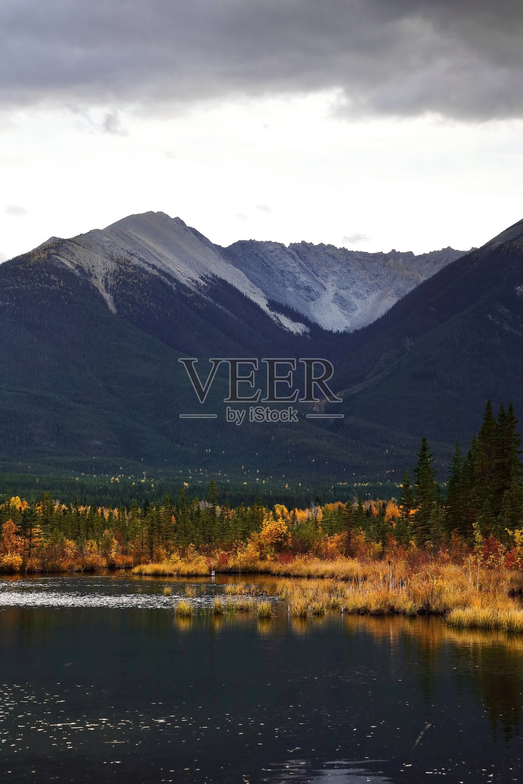 从维尔米利翁湖三号西端的黑暗水面上看，日落时分的桑丹斯山脉西北端的山峰。班夫，阿尔伯塔，加拿大-A07照片摄影图片