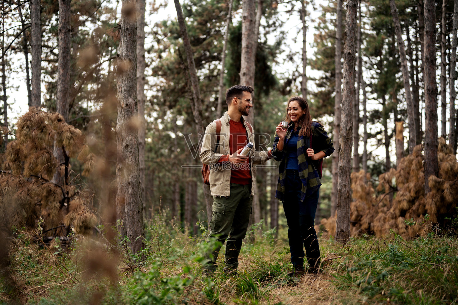 年轻情侣在大自然中休息，喝水以缓解长途徒步的疲惫照片摄影图片