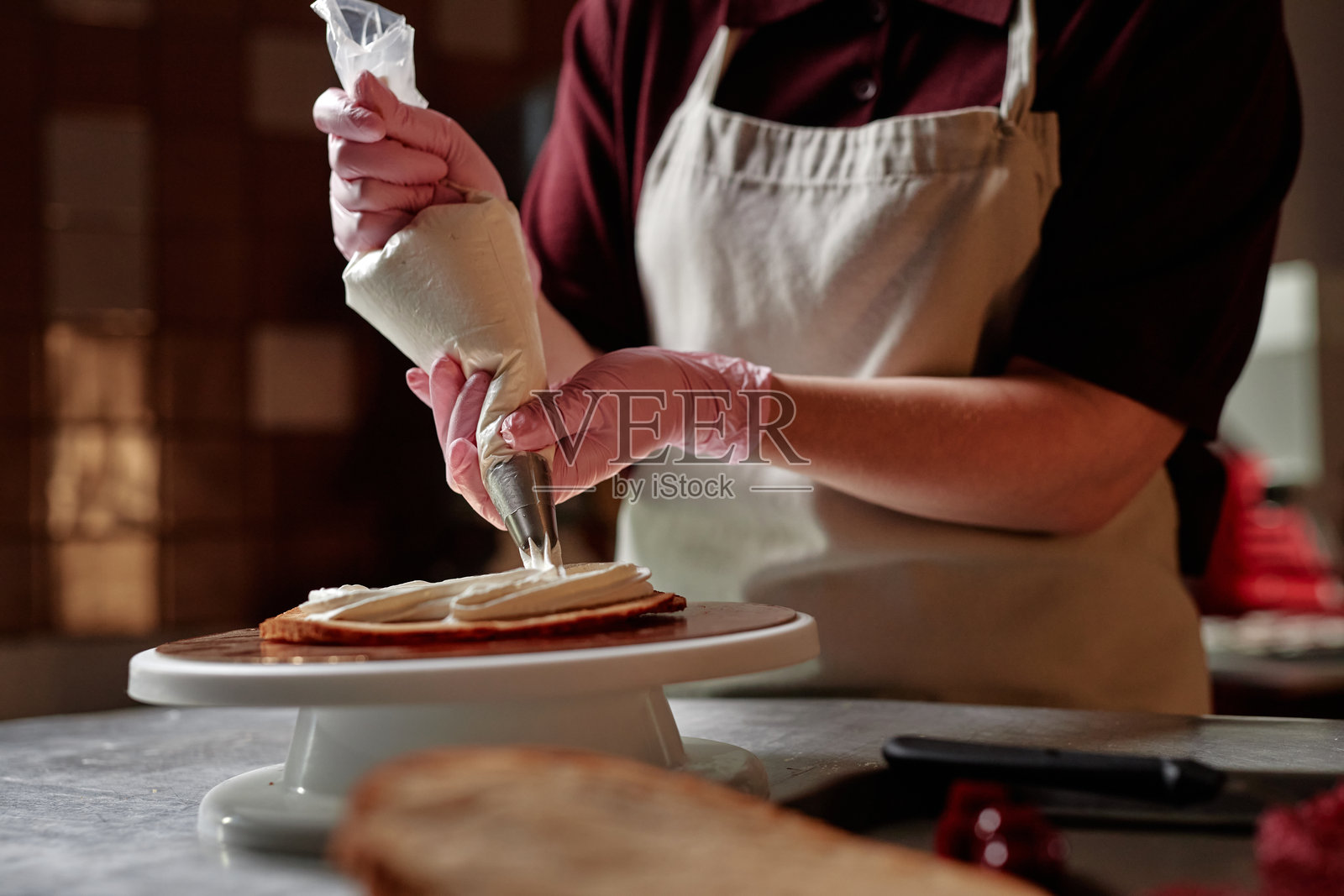 女性糕点厨师的手在室内用裱花袋为蛋糕层叠奶油装饰照片摄影图片