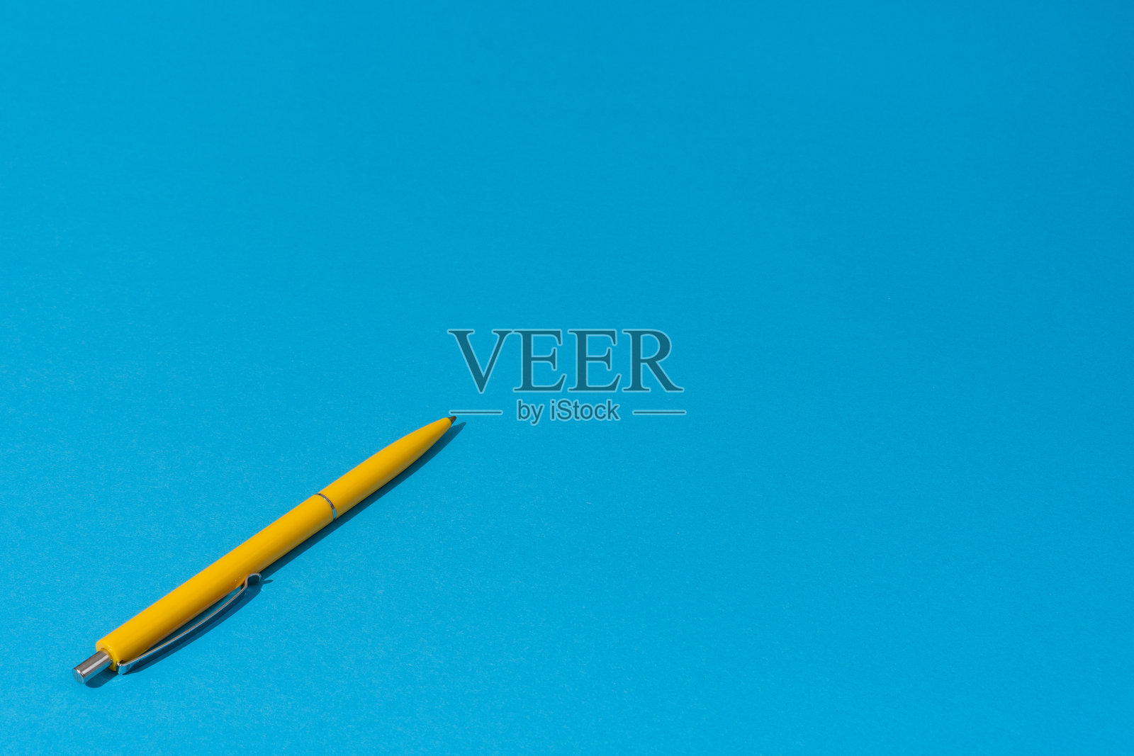 蓝色背景上的黄色圆珠笔照片，留有空白空间。照片摄影图片