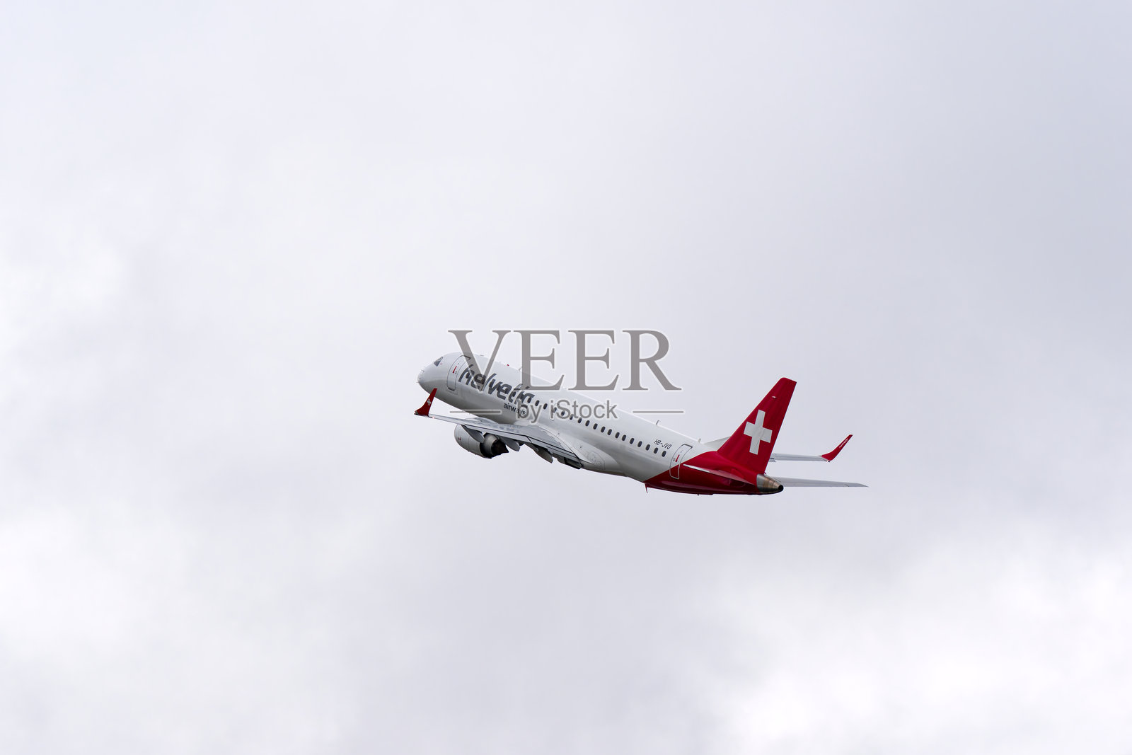 Ascending Helvetic Airways passenger airplane Embraer ERJ-190 registration HB-JVO taking off from Swiss Airport Zürich Kloten on a cloudy winter day.照片摄影图片