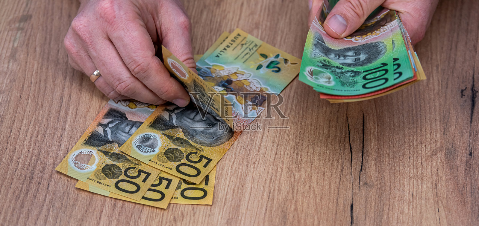 男人在数澳大利亚元纸币，50和100新澳大利亚元。照片摄影图片