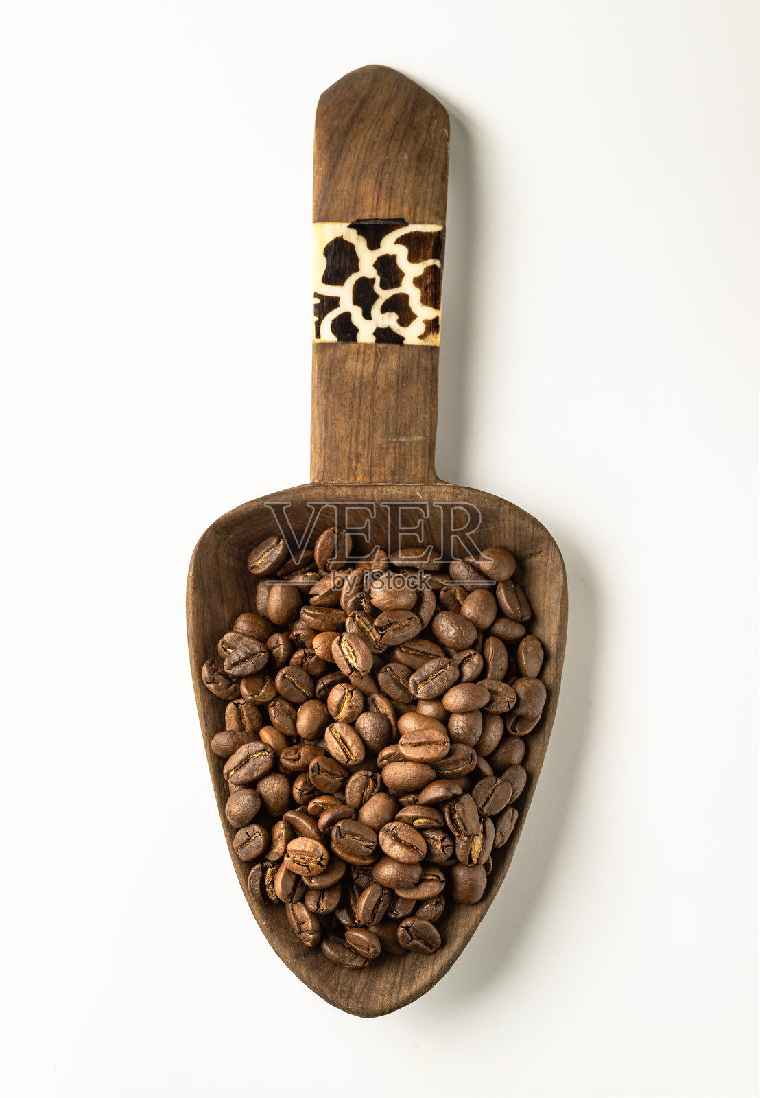 白色背景上，木制咖啡勺中盛放着烘焙咖啡豆，周围是丰富的纹理表面。照片摄影图片