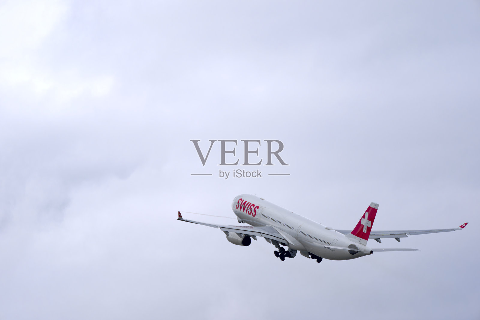 在一个多云的冬日，仰望瑞士客机空客A330-343，注册号HB-JHJ，从瑞士苏黎世克洛滕机场起飞。照片摄影图片