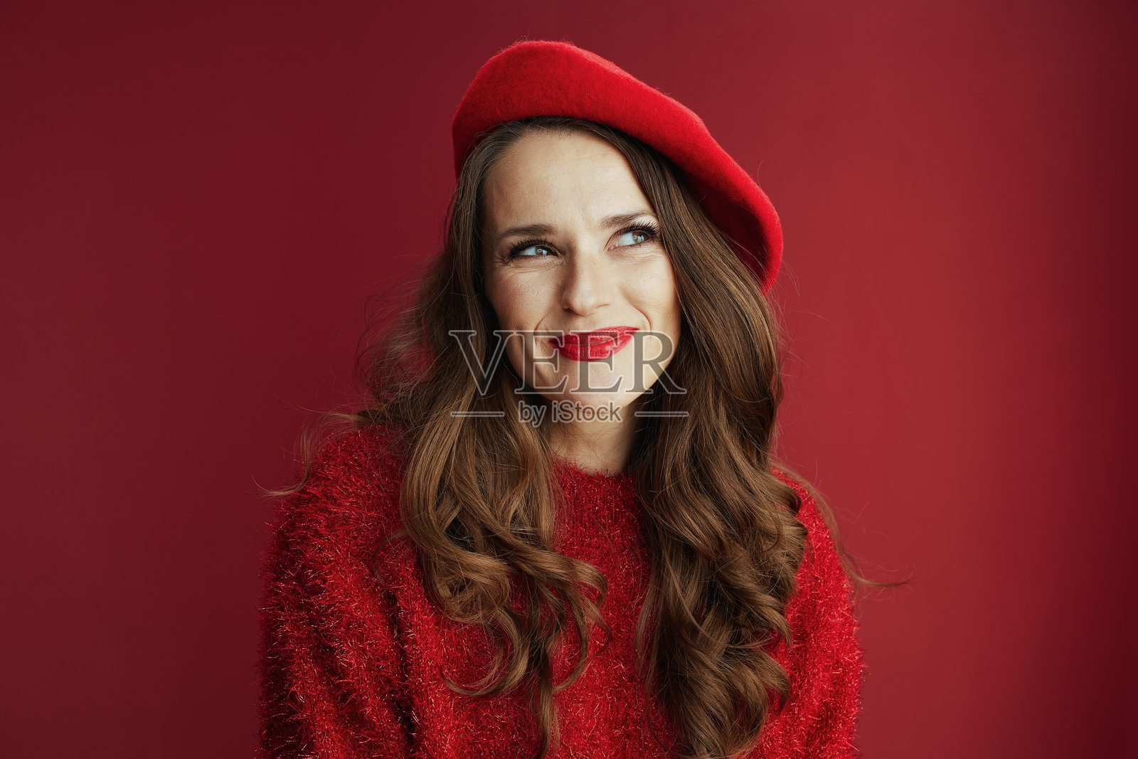 穿着毛衣和贝雷帽的快乐女性在背景前。照片摄影图片