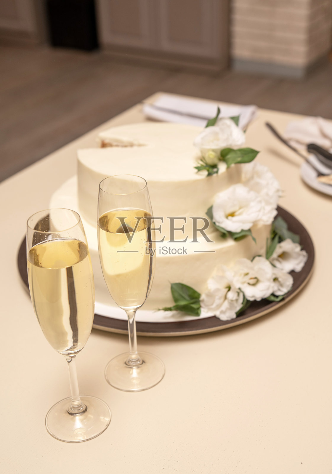 桌子上放着两个香槟杯和一个蛋糕照片摄影图片