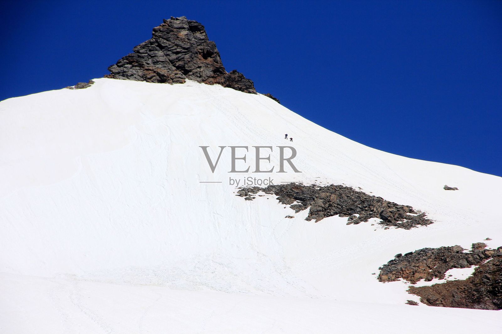 一个男人在阳光明媚的蓝天下滑雪下陡峭的山。照片摄影图片