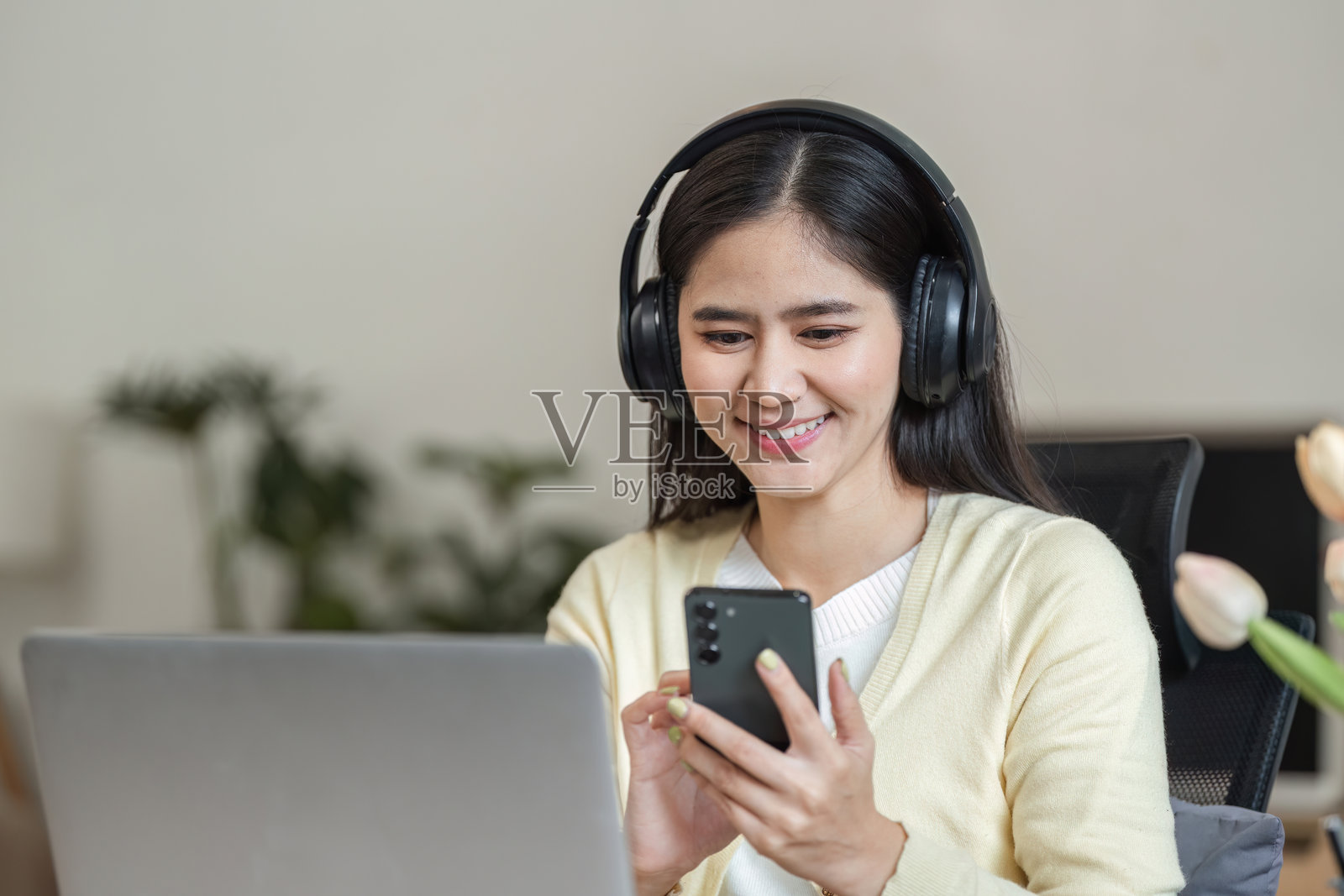 微笑的女商人使用智能手机在家工作，享受远程工作的生活。照片摄影图片