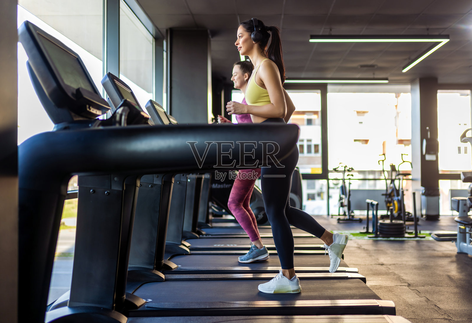 两名女性在跑步机上跑步。照片摄影图片