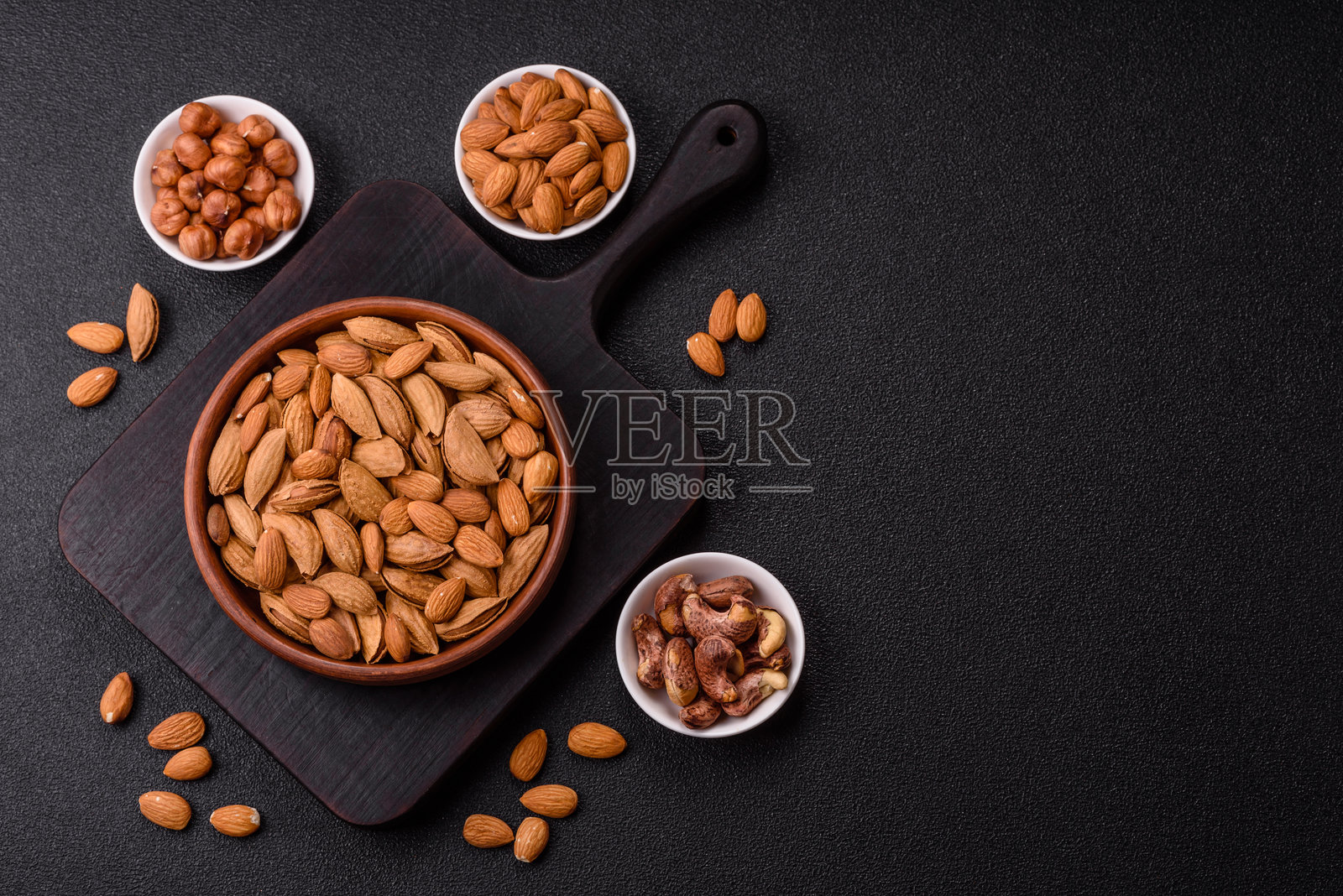 碗中装有烤制或生的带壳杏仁。照片摄影图片