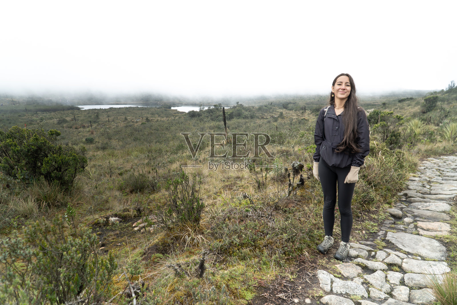微笑的徒步旅行者享受着雾气弥漫的山景。西班牙裔旅行者在雾中的山上。照片摄影图片