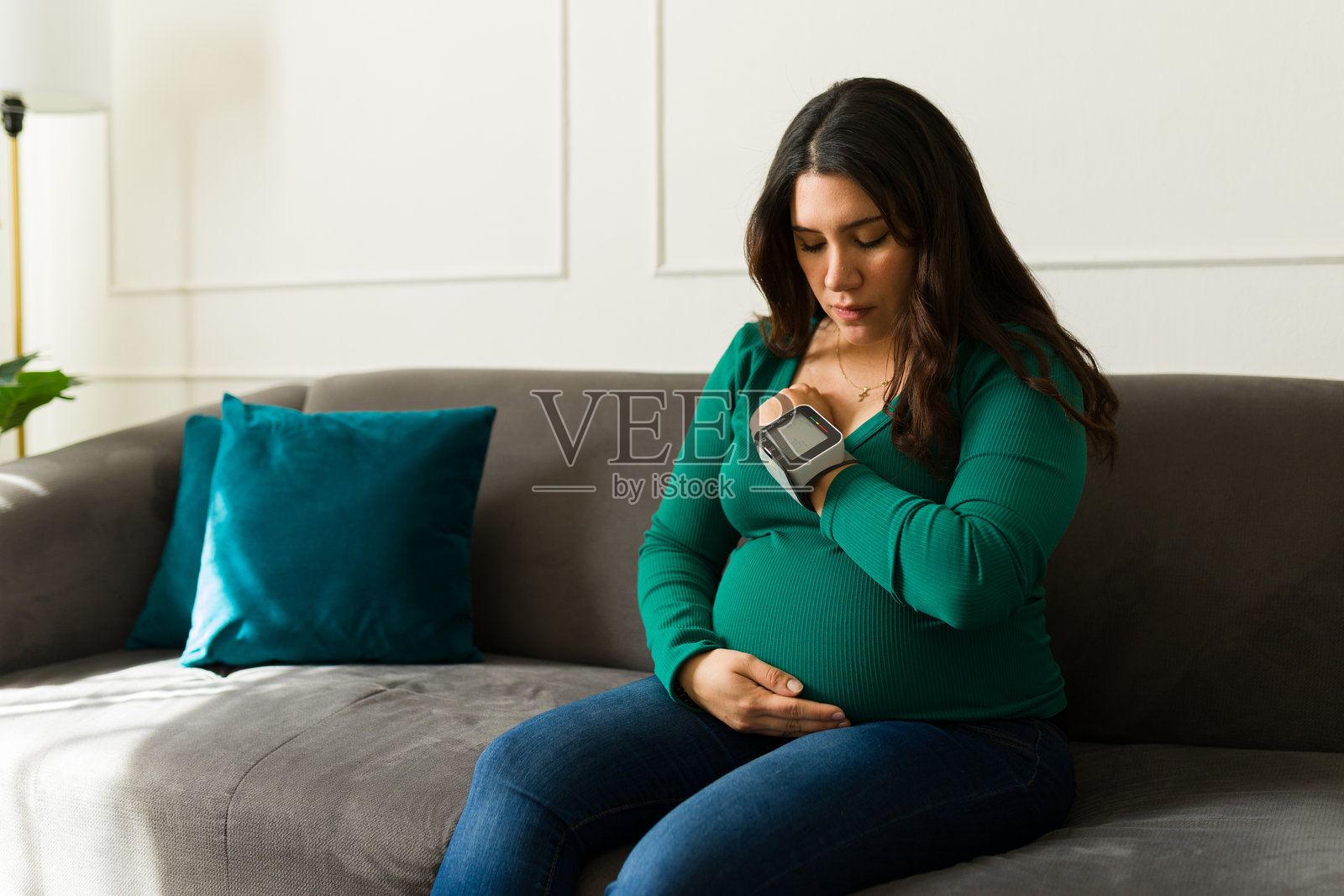 担心的孕妇在家使用便携式血压监测仪，关注怀孕期间的健康照片摄影图片