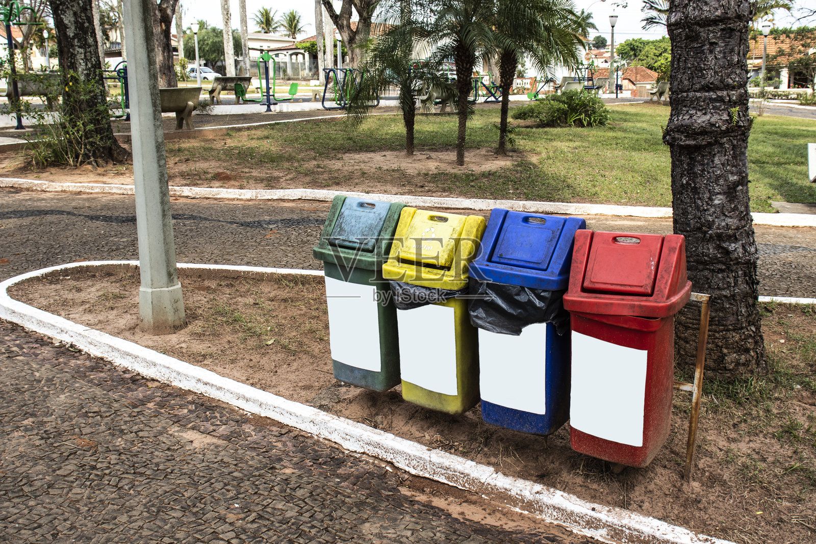 旧而脏的四色垃圾桶用于回收，标有塑料、纸张、玻璃和金属字样照片摄影图片