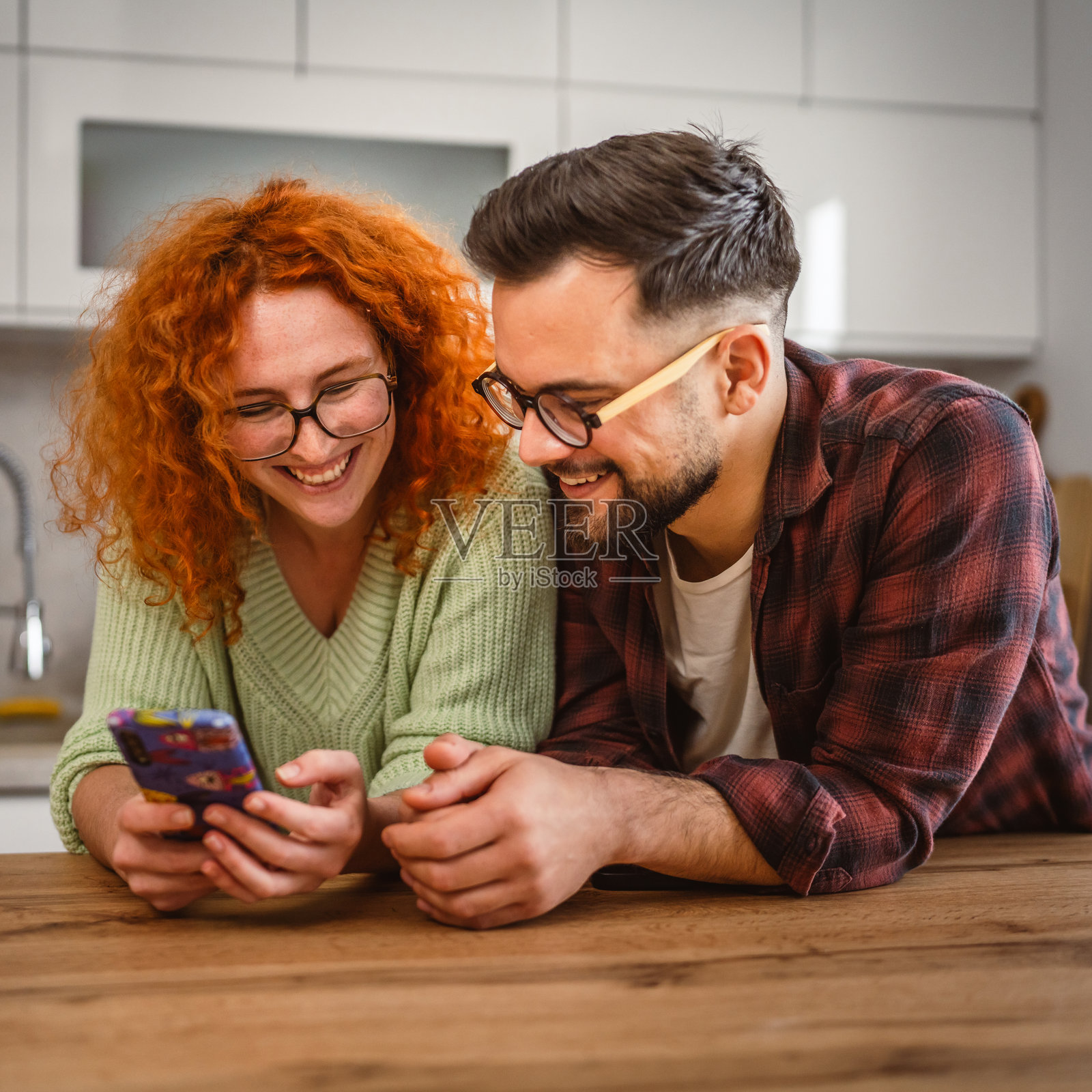 美丽年轻快乐的情侣在厨房里一起使用手机照片摄影图片