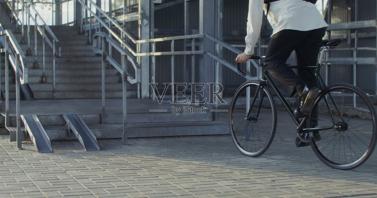 一个男人骑自行车到梯子旁，抱起自行车并将其搬上去。照片摄影图片