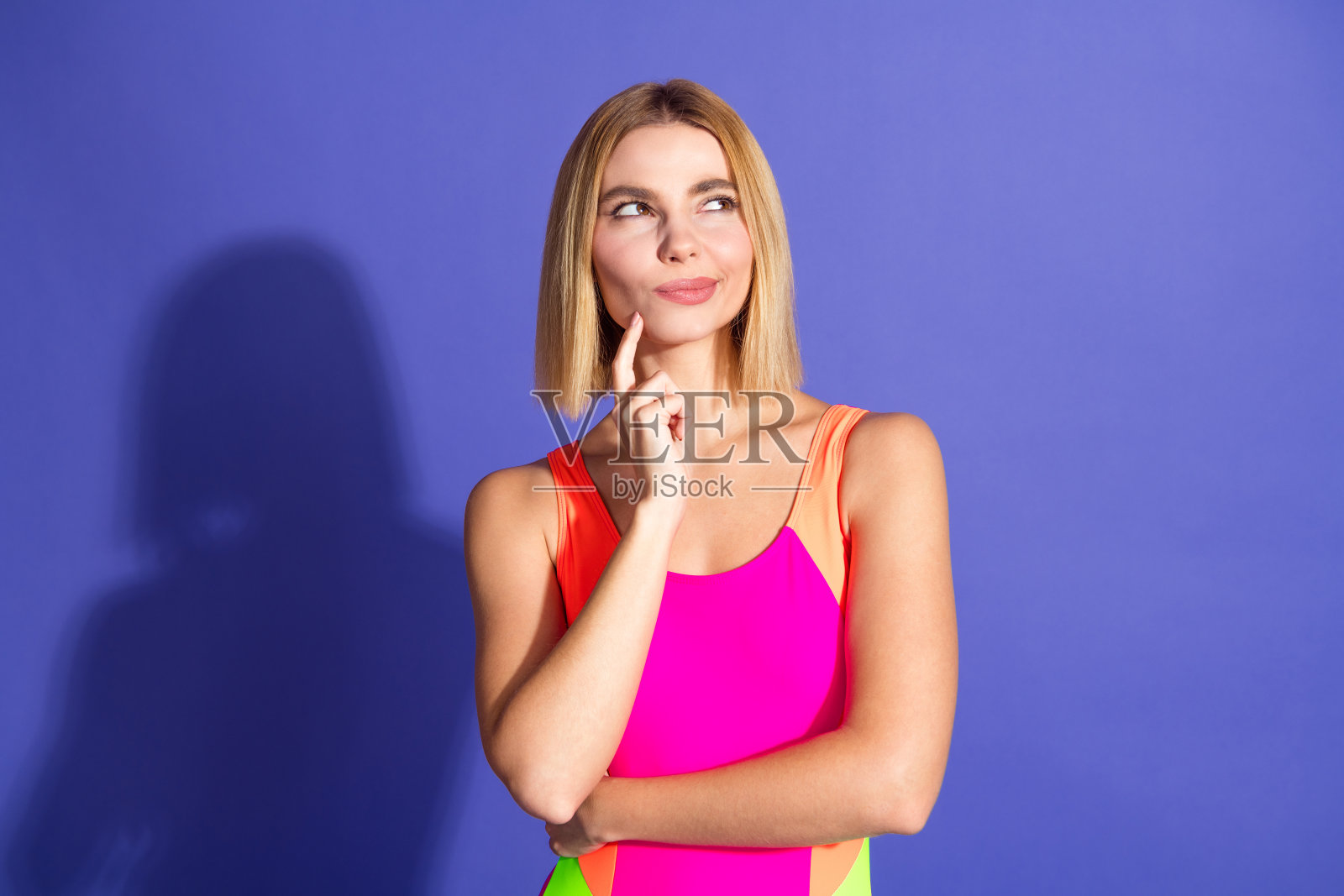 年轻时尚女性穿着色彩斑斓的服装，站在充满活力的紫色背景前，散发出自信与魅力。照片摄影图片