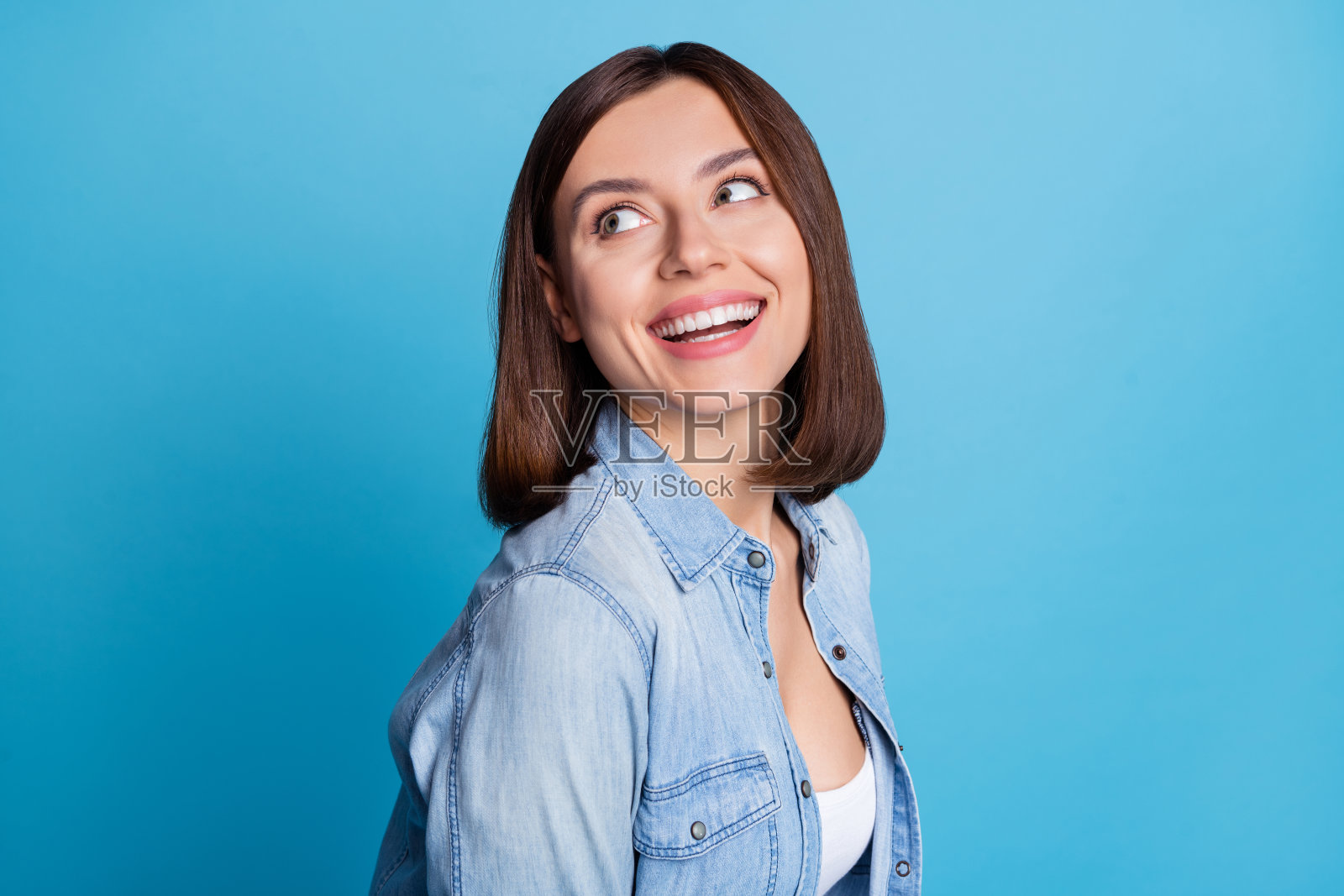 积极漂亮女孩的头像照片，目光投向空旷的空间，背景为蓝色。照片摄影图片