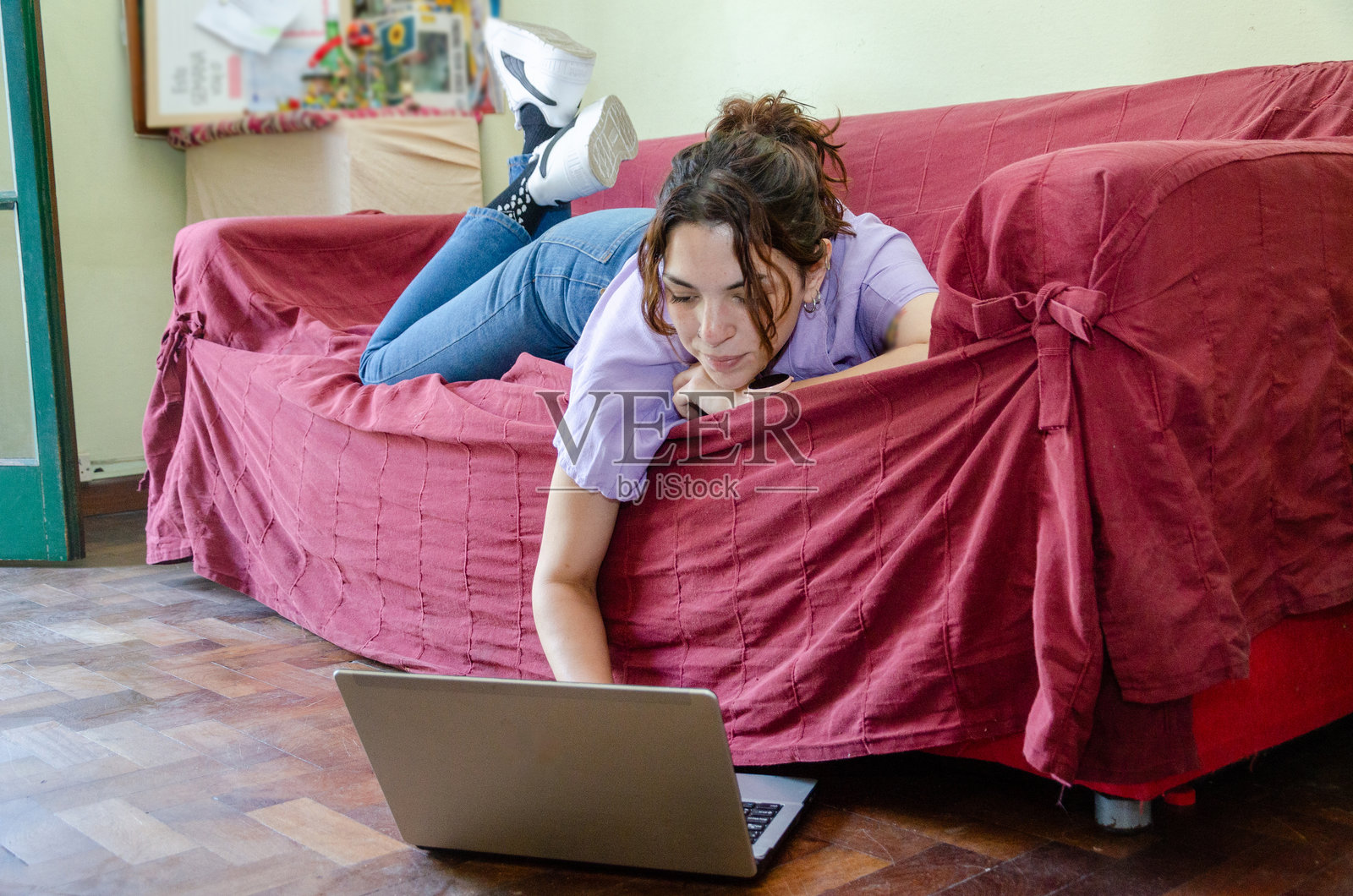 放松的女性员工或学生在家里的沙发上使用笔记本电脑工作照片摄影图片