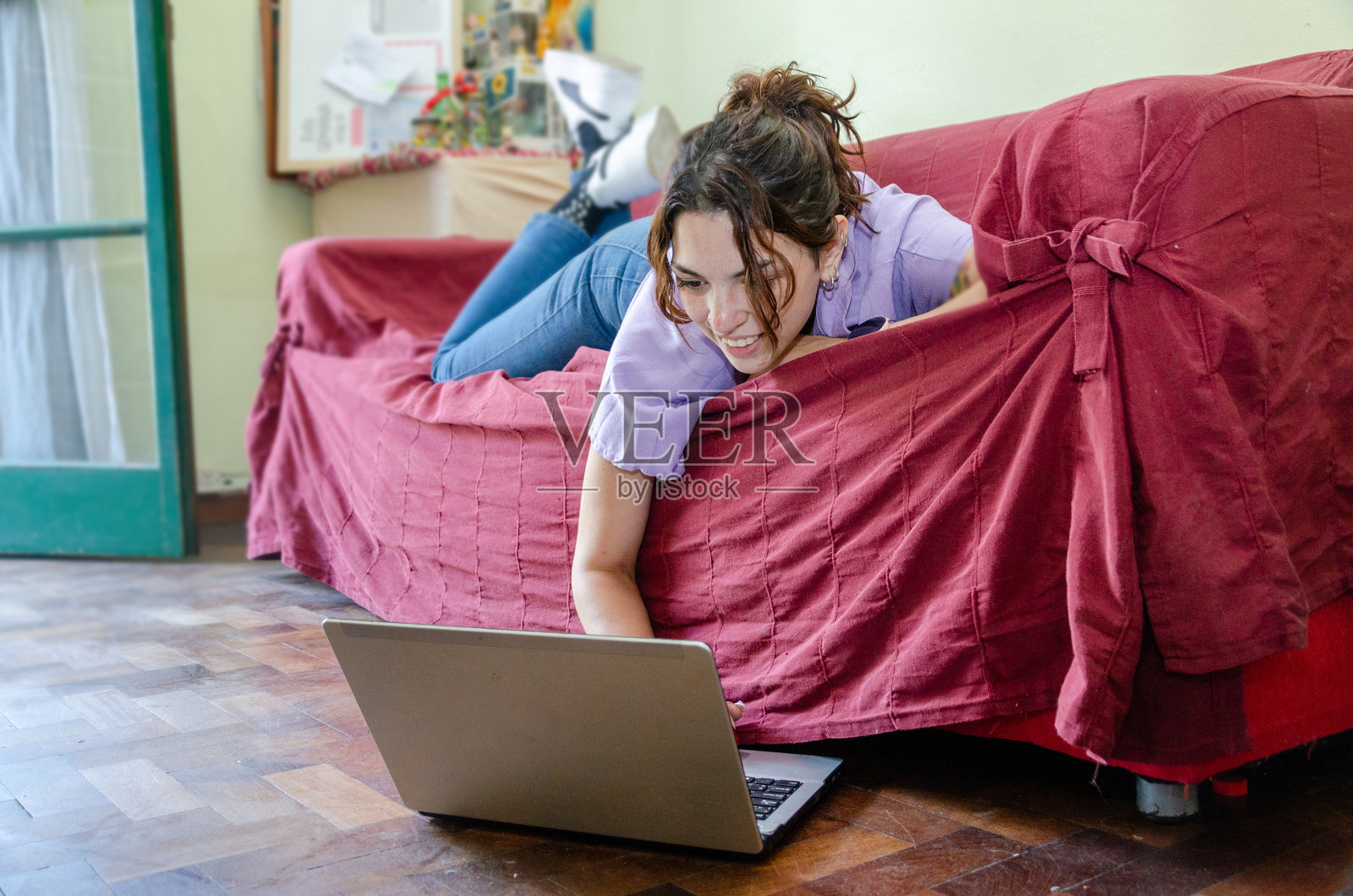 放松的女性员工或学生在家里的沙发上使用笔记本电脑工作照片摄影图片