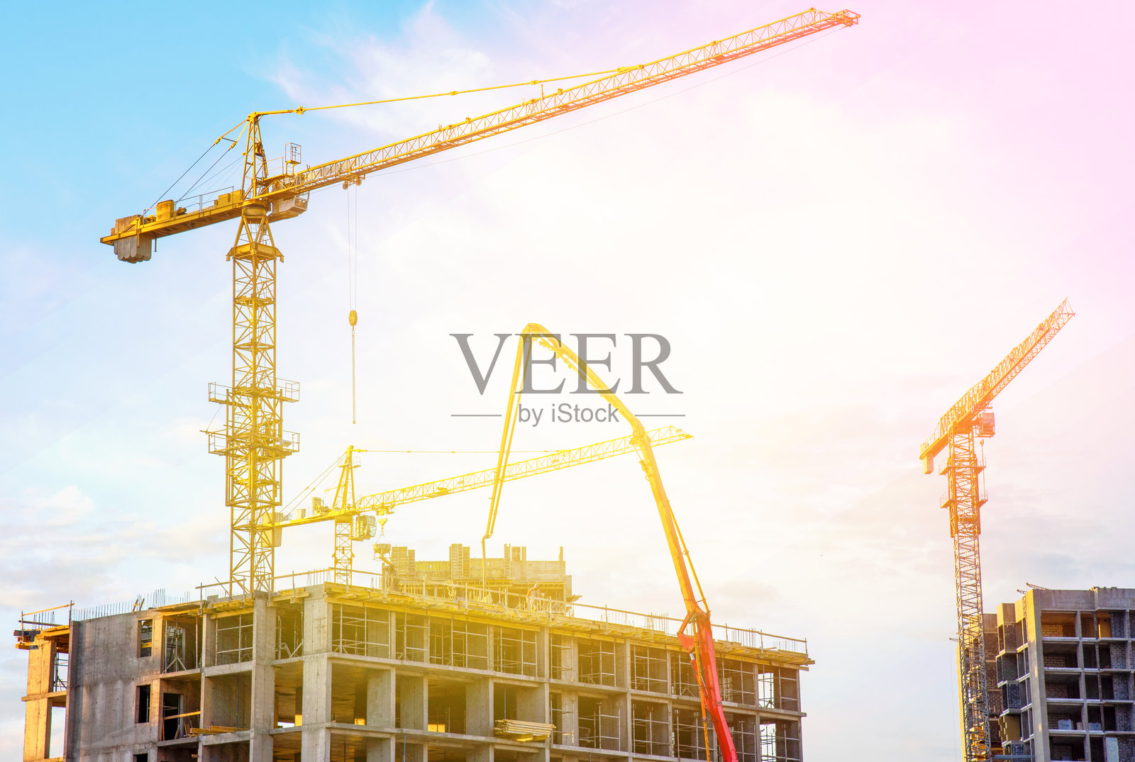 建筑工地上的塔吊。日落时分的施工现场。照片摄影图片