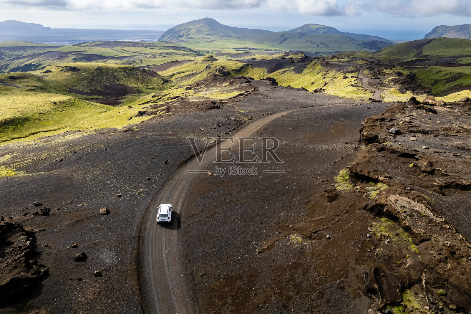 无人机航拍探索冰岛维克附近的塔克吉尔（Pakgil）露营地的山谷景观，孤独的白色四驱车在土路上行驶。照片摄影图片