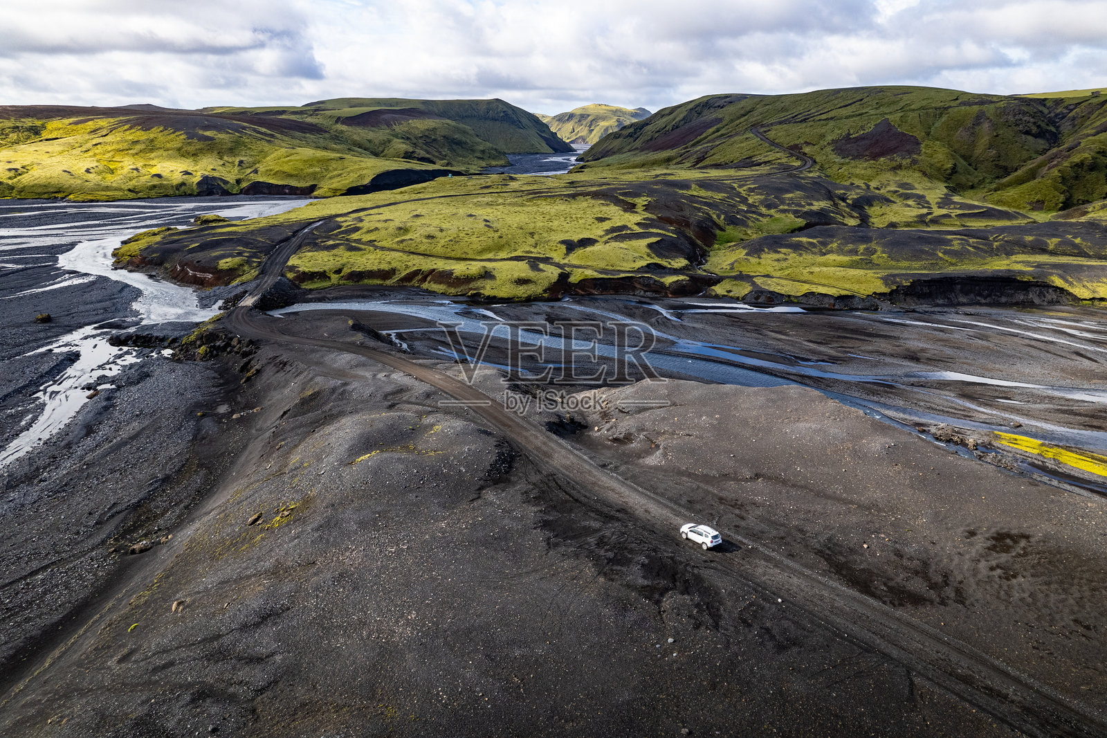 无人机航拍探索冰岛维克附近的塔基尔（Pakgil）露营地的河谷风景，孤独的白色四驱车在土路上行驶。照片摄影图片