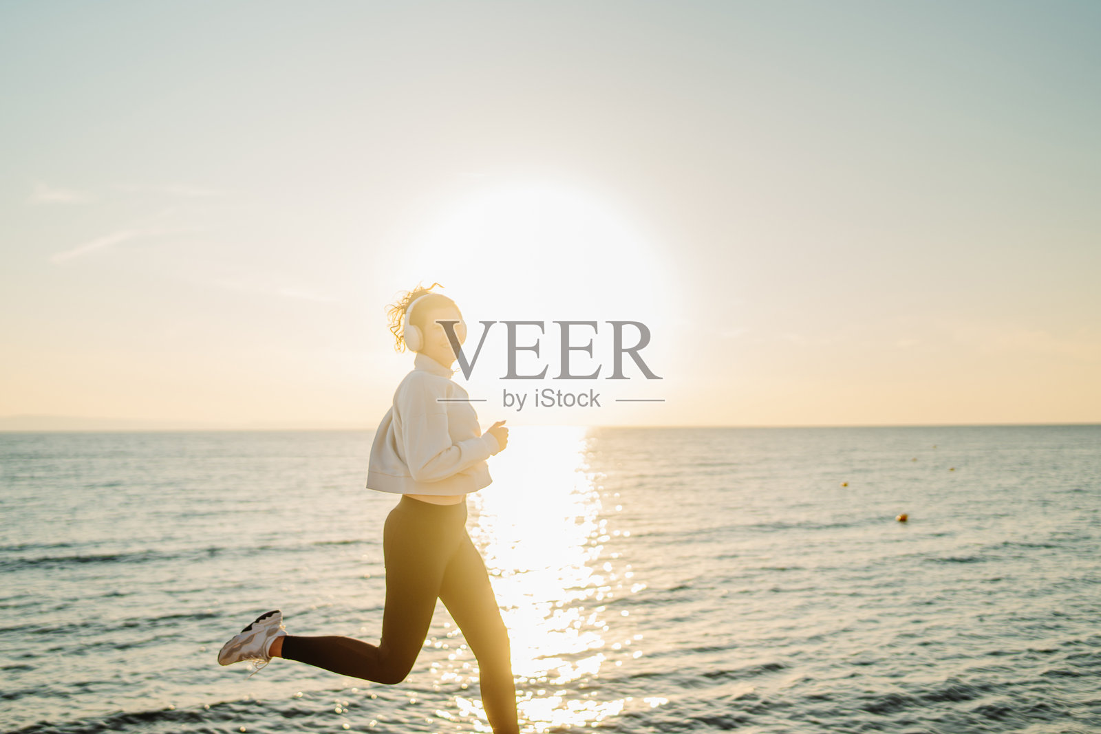 年轻的白人女性在日落时分的海滩上跑步或慢跑照片摄影图片