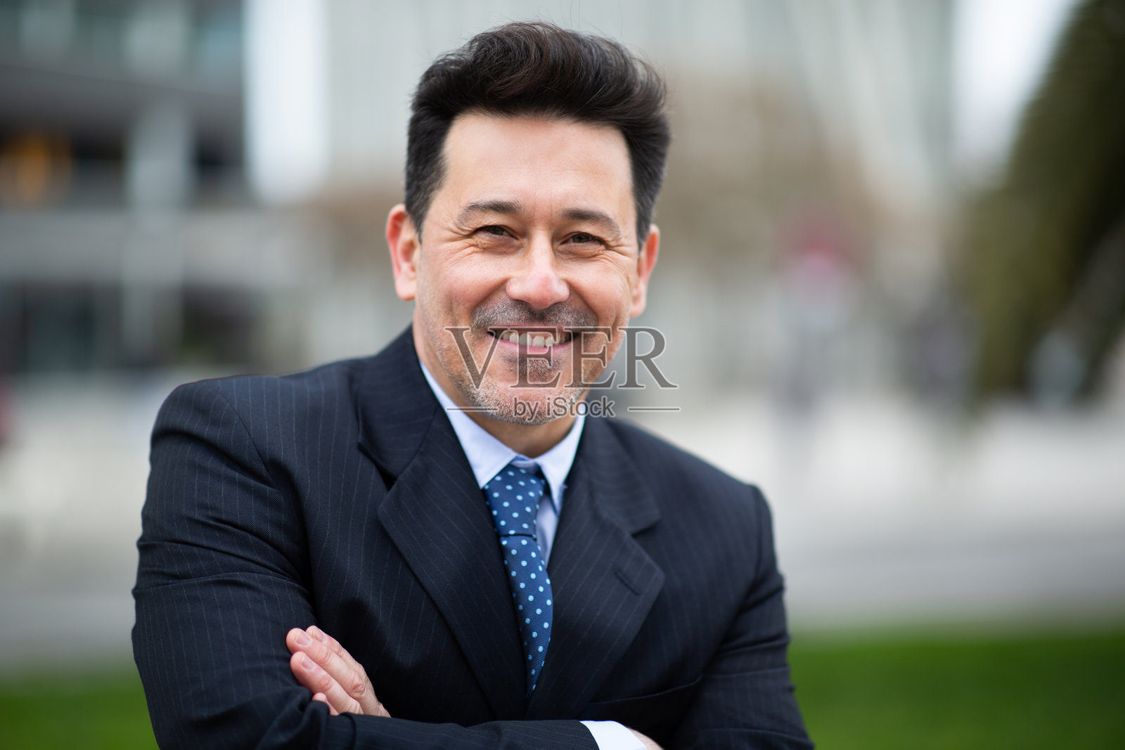 微笑的成熟商人在外面双臂交叉站立照片摄影图片