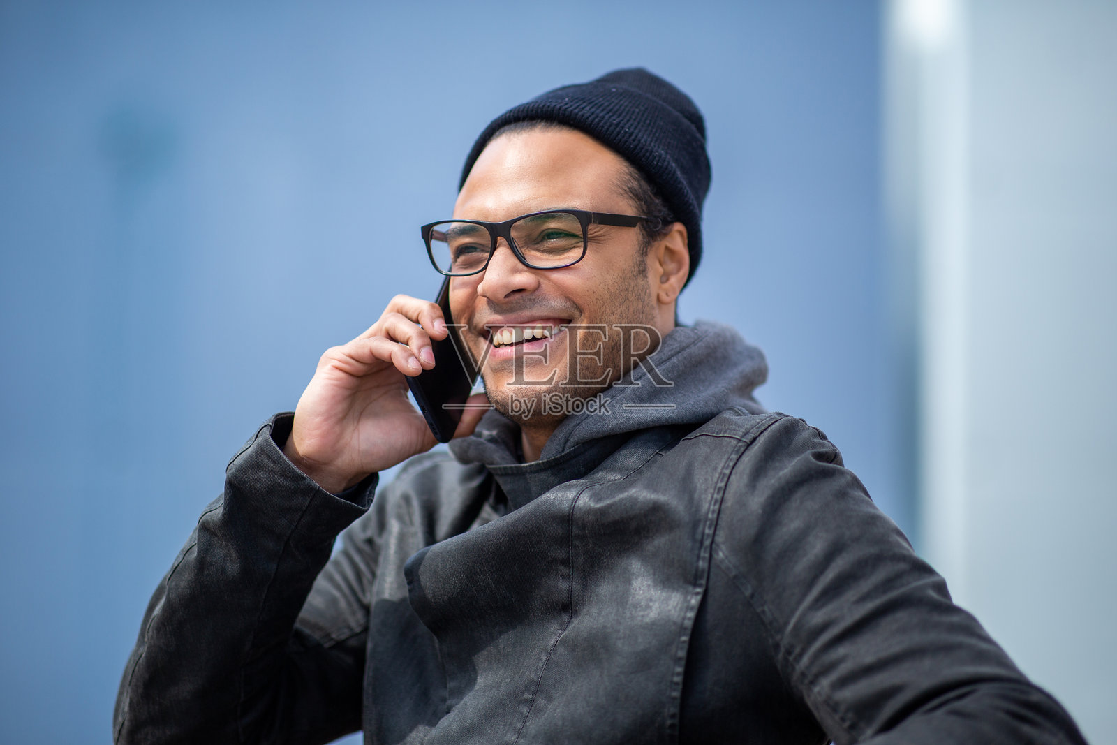 穿着温暖衣物的快乐非洲男子在户外打手机。照片摄影图片