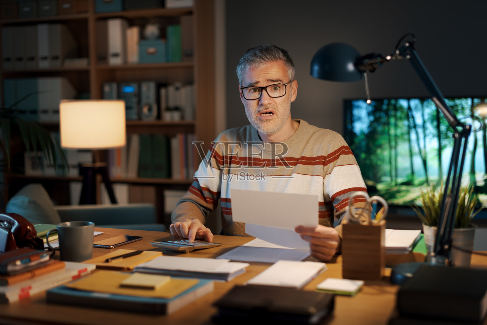 感到压力的男人在查看一份昂贵的账单照片摄影图片