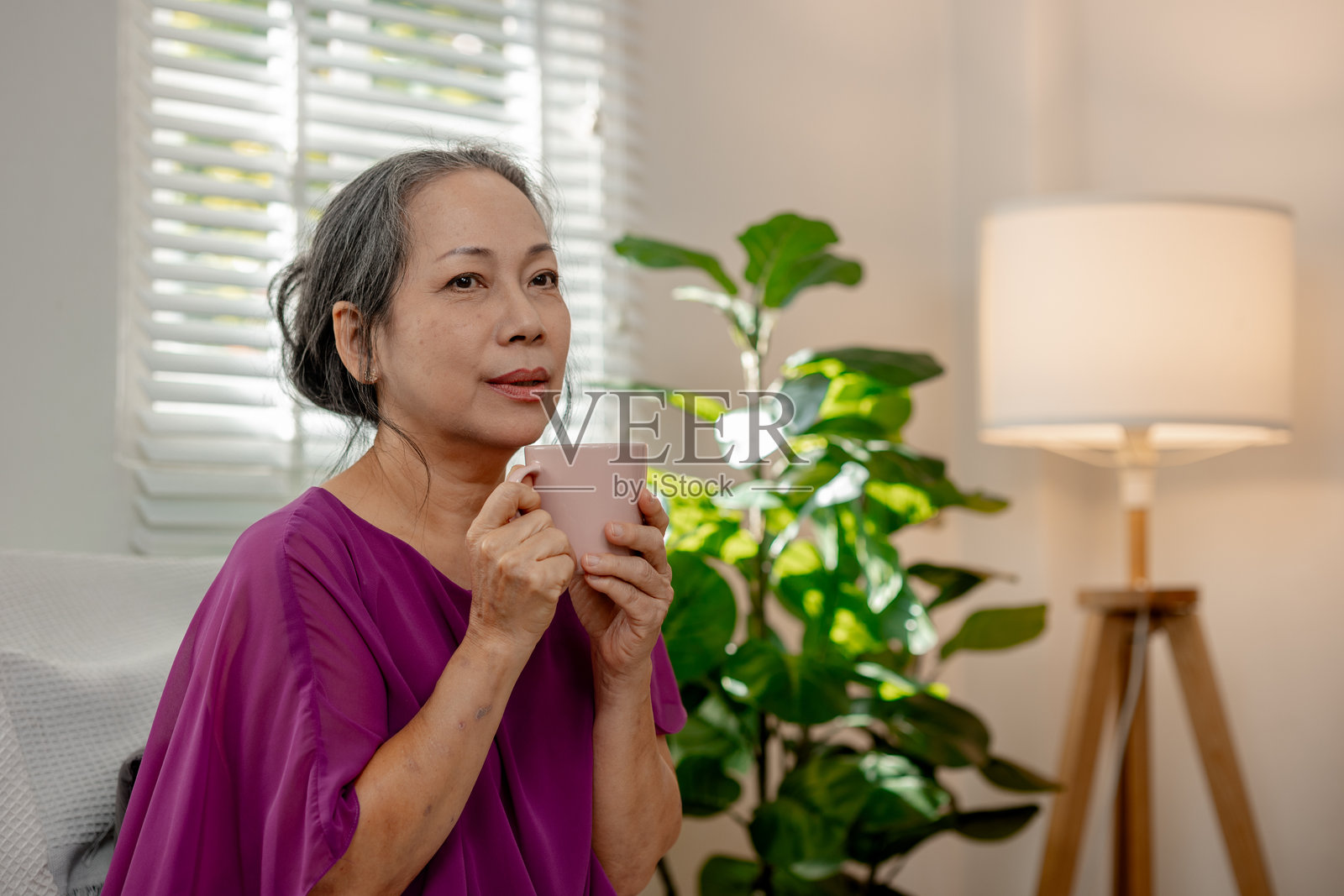 一位善良的老年女性在自己家中悠闲地度过闲暇时光，享受各种活动，展现了退休生活的快乐与品质。照片摄影图片