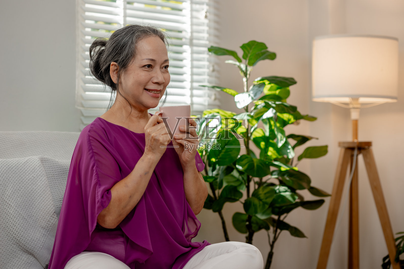 一位善良的老年女性在自己家中悠闲地度过空闲时间，享受各种活动，展现了退休老人的快乐和高质量生活。照片摄影图片
