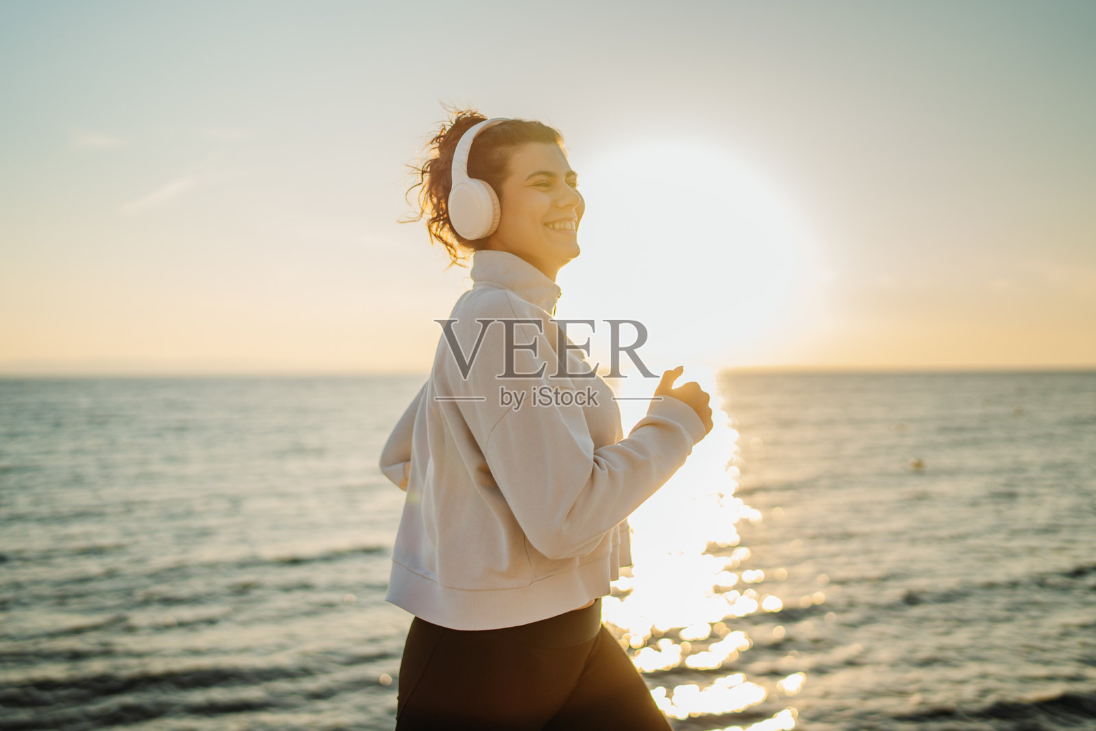 年轻的白人女性在日落时分在海滩上跑步或慢跑照片摄影图片