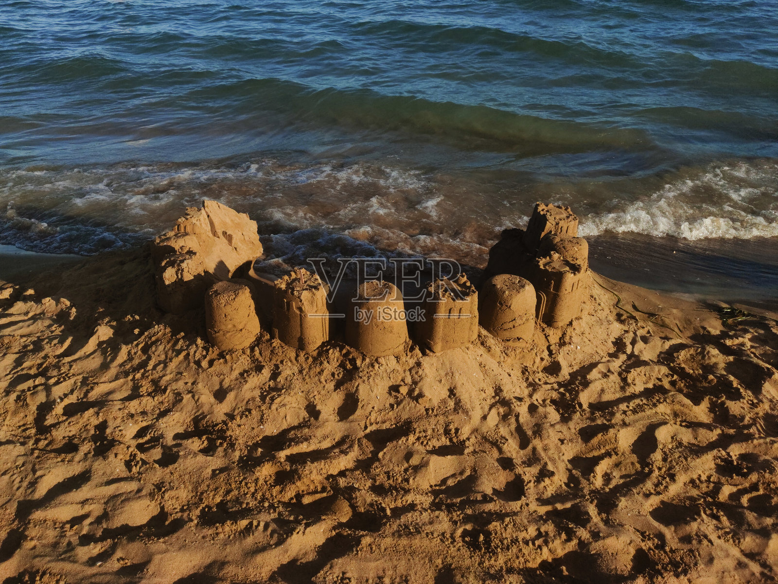 坚固的沙堡矗立在柔和的亚得里亚海浪中，坐落在比比奥内海岸的金色沙滩上照片摄影图片