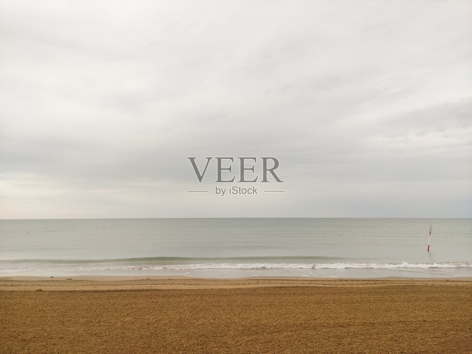 意大利比比奥海滩上，平静的海浪轻轻拍打着沙滩，天空布满云彩。照片摄影图片