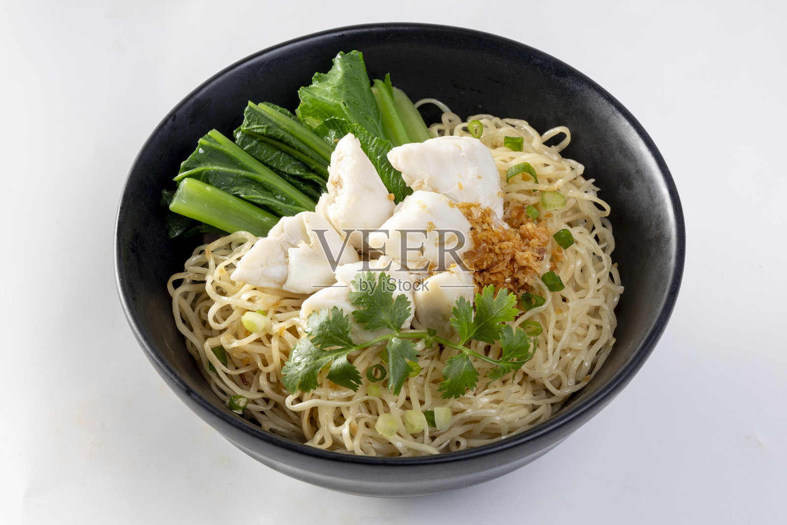 碗里盛着中国蛋面，上面放有切片的红烧猪肉、猪肉云吞和白色蟹肉。照片摄影图片