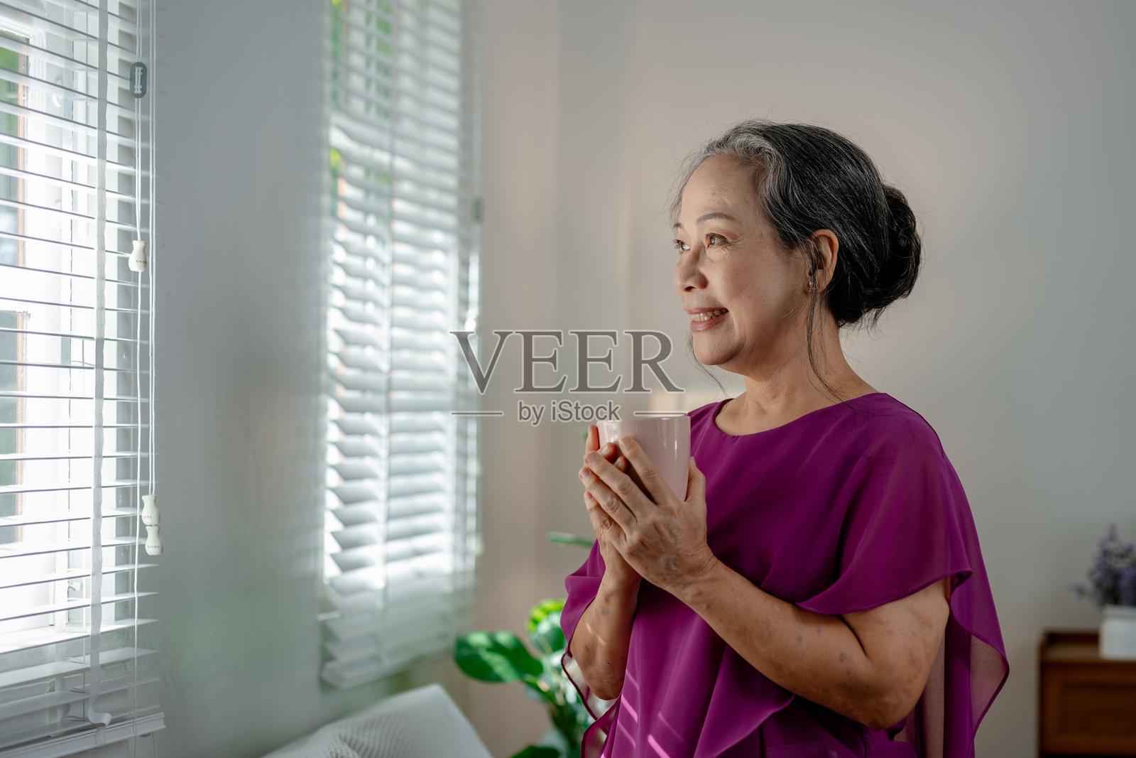 一位善良的老年女性在自己家中悠闲地度过空闲时间，享受各种活动，展现了退休老人的幸福和高质量生活。照片摄影图片