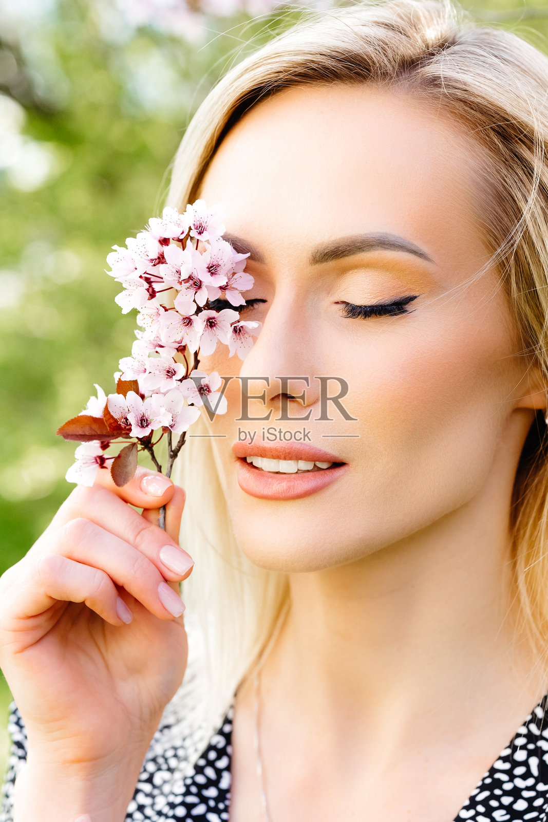 美丽的金发女人在眼前捧着樱花照片摄影图片