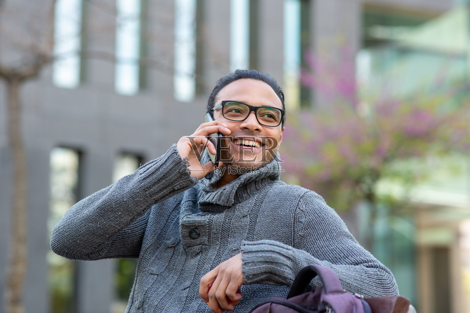 年轻的非洲男子坐在城市的长椅上打电话照片摄影图片