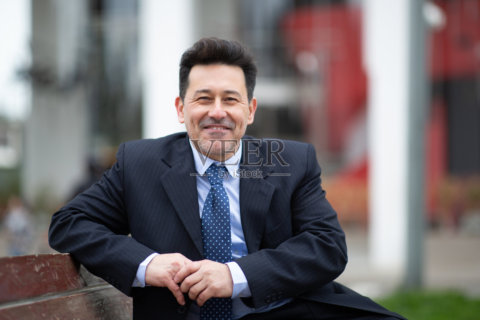 自信的拉丁裔商人在城市的长椅上坐着照片摄影图片