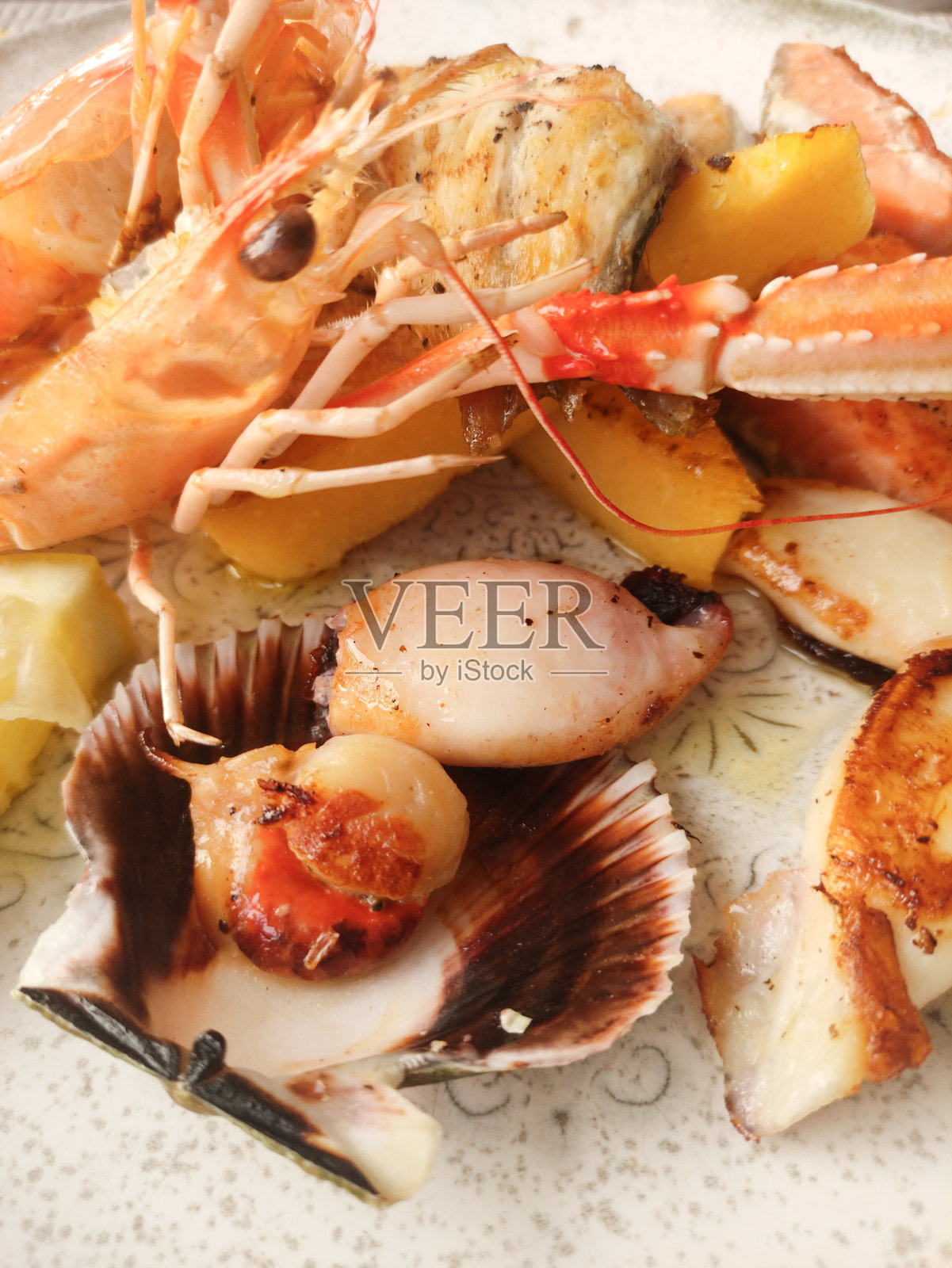 美味海鲜拼盘特写，包含烤虾、扇贝和柠檬角，展示了意大利比比奥内的烹饪艺术。照片摄影图片