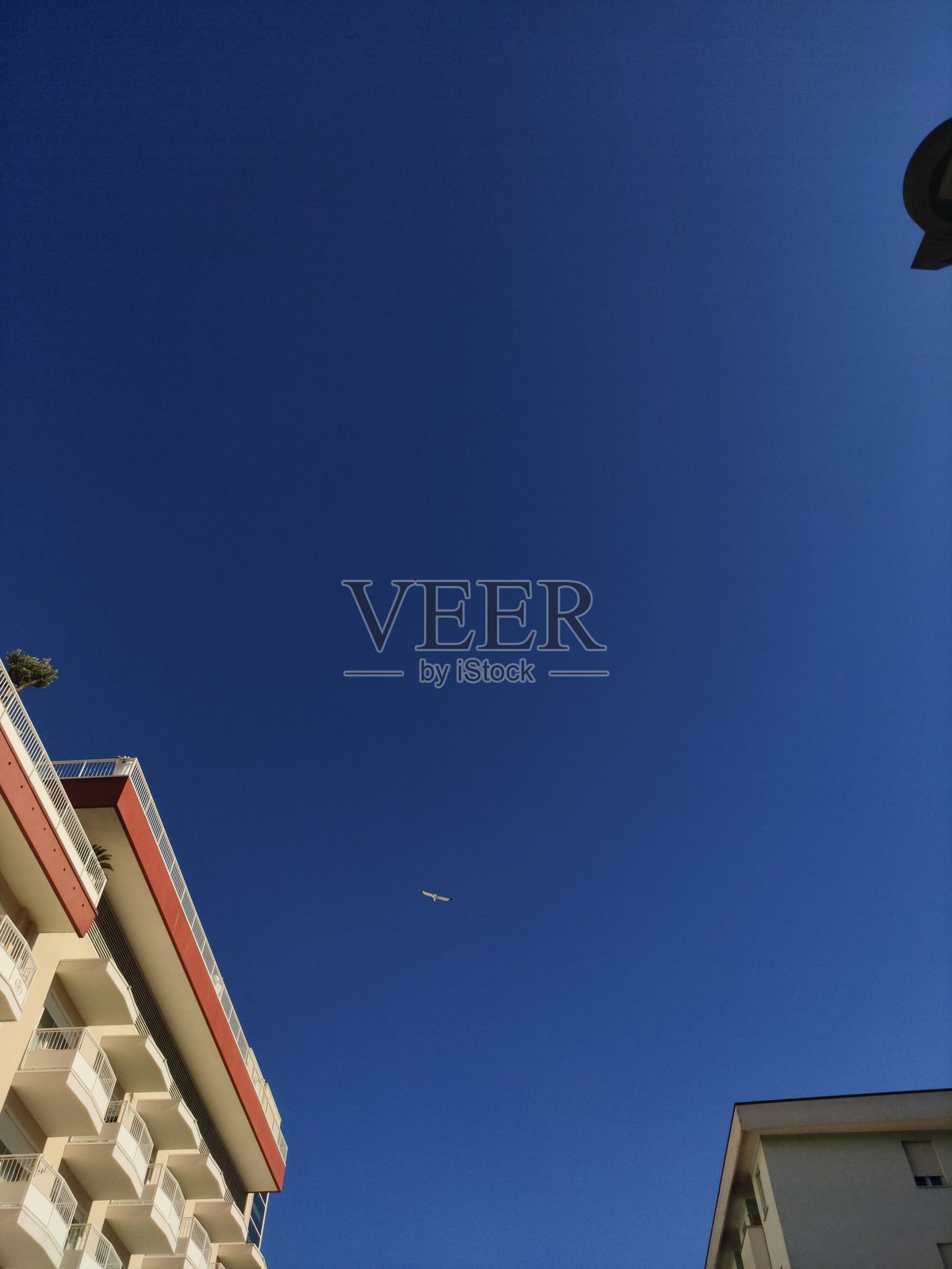 意大利比比奥内上空飞过的客机，明亮的蓝色夏季天空衬托出建筑景观。照片摄影图片