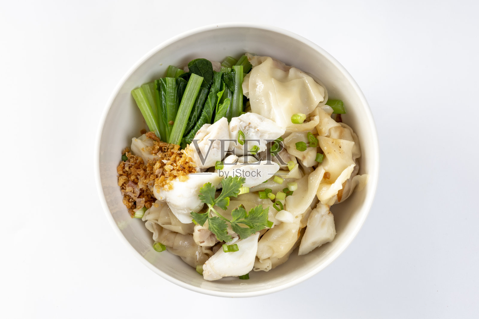 碗里盛着中国蛋面，上面放有切片的红烧猪肉、猪肉云吞和白色蟹肉。照片摄影图片