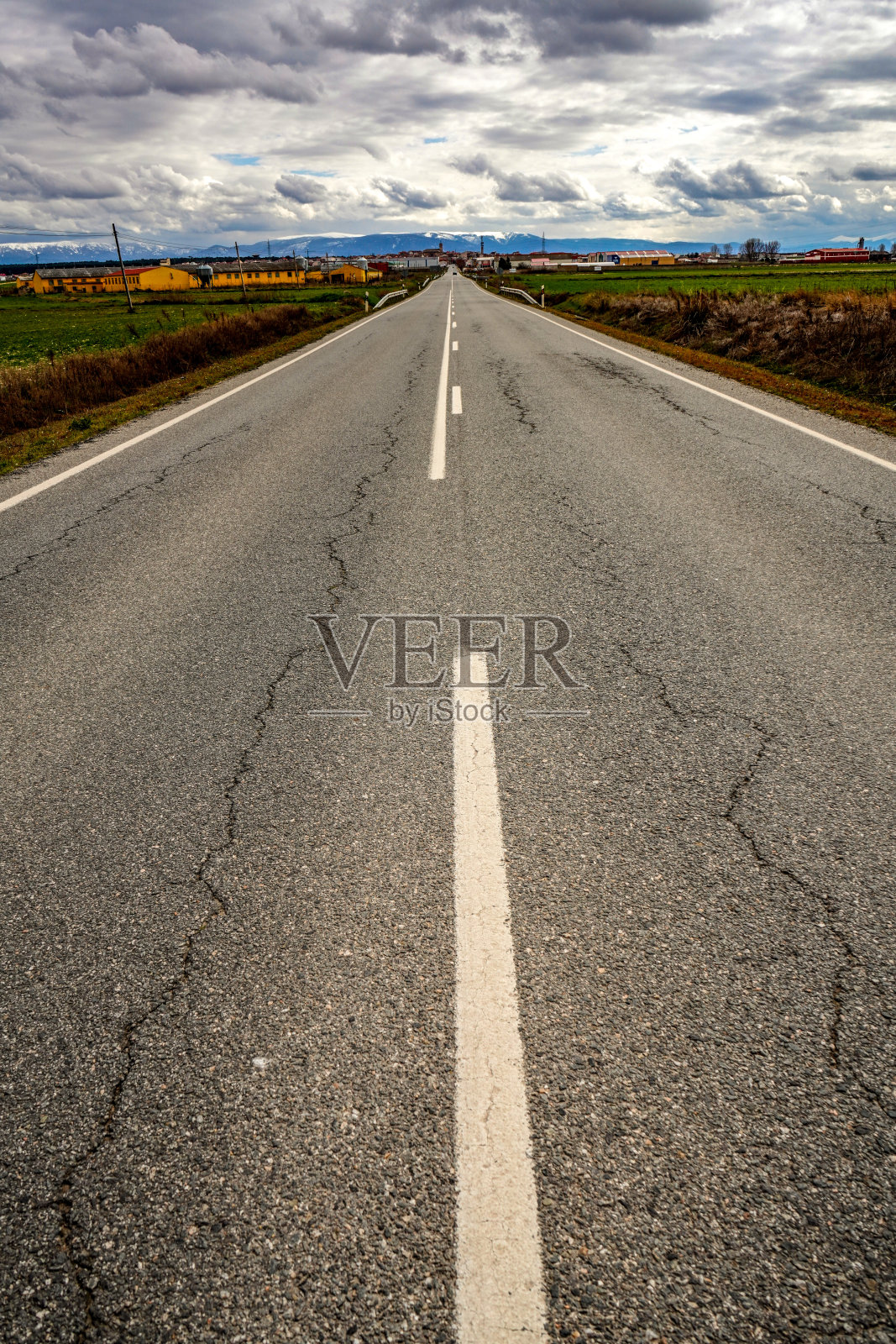 阴天草地间的沥青道路照片摄影图片