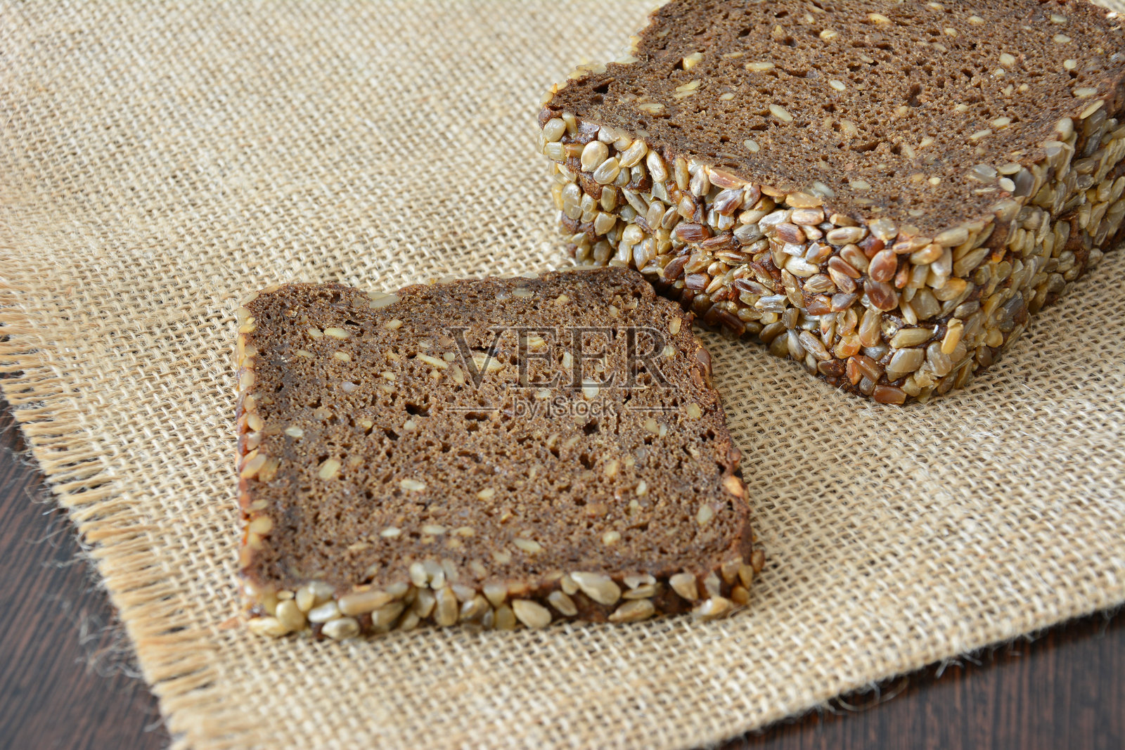 切片黑麦面包上撒有向日葵种子的特写，背景为乡村风格照片摄影图片