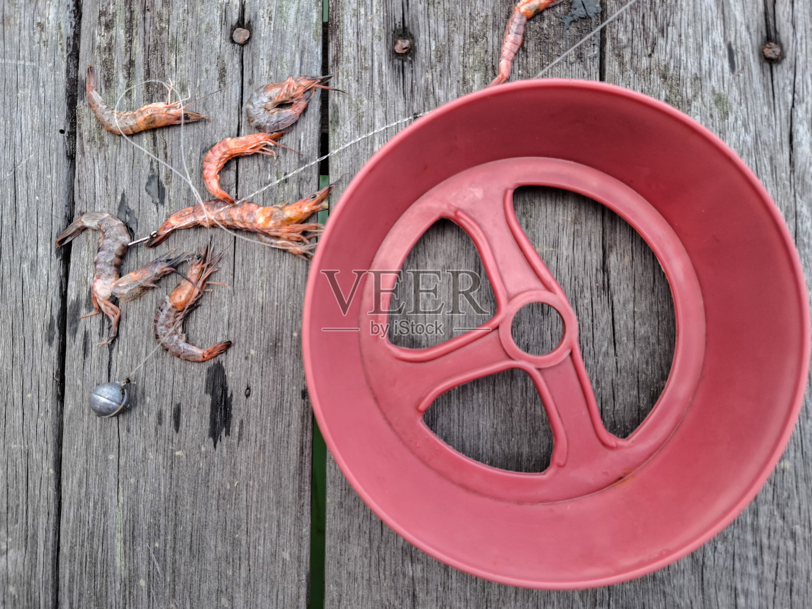 传统红色钓竿，配有线轮、虾饵和铅坠。照片摄影图片