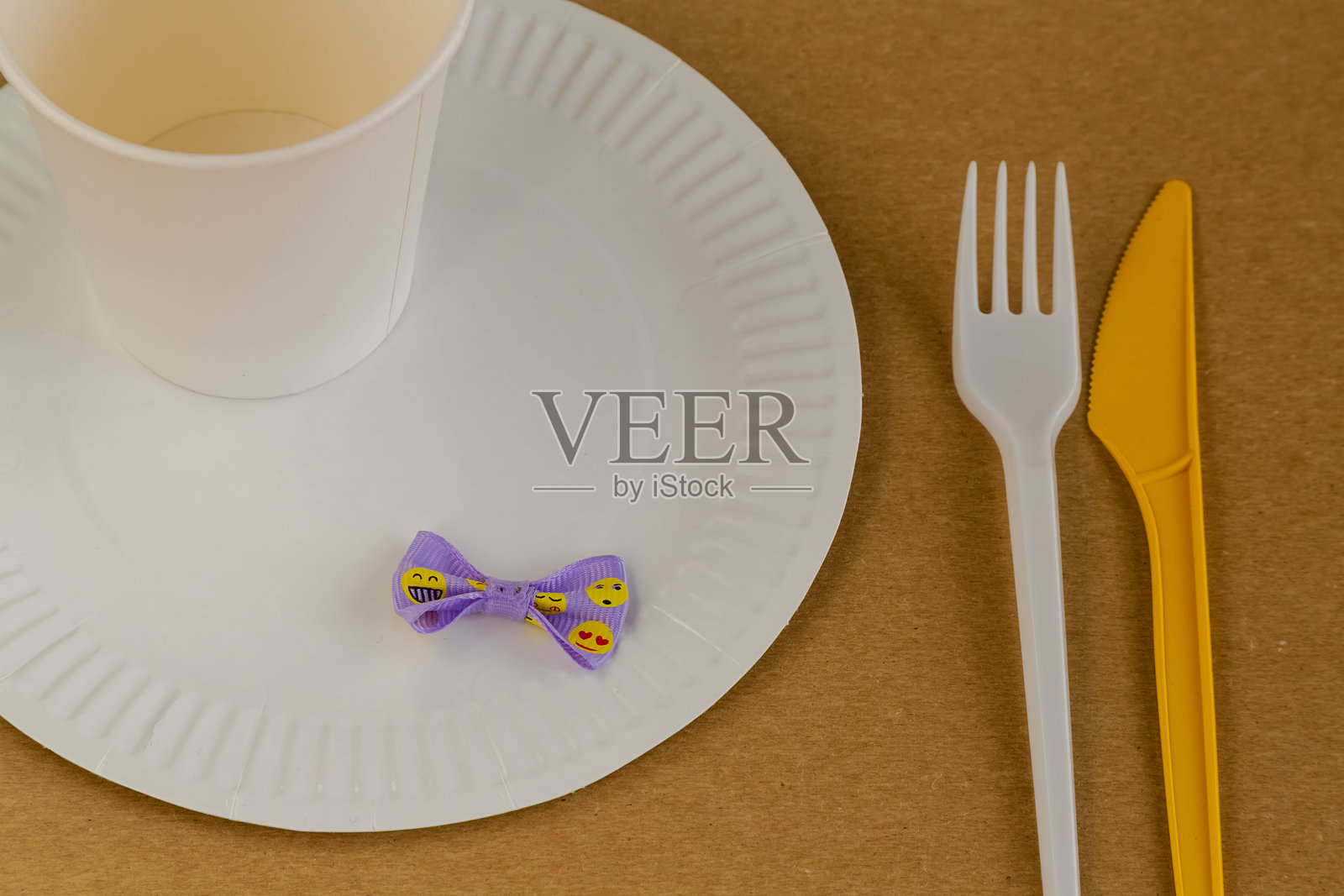 一个带有表情符号的欢快丝带装饰着简单的一次性餐具和饼干。它象征着节日的准备、办公室生日和特殊的氛围。照片摄影图片